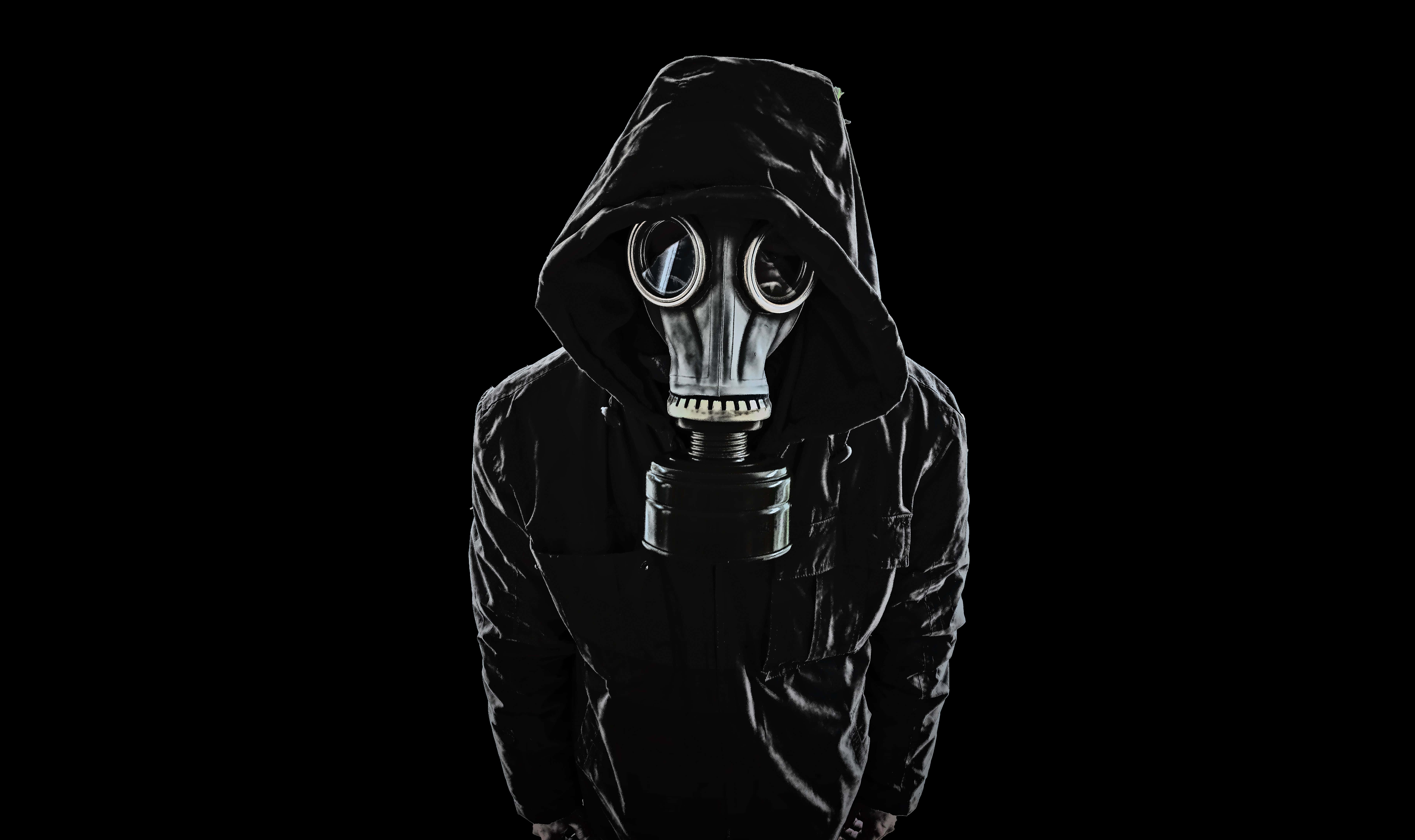 Mask 桌布 壁紙 — 一個穿著黑色連帽外套的人，在純黑色背景前戴著金屬防毒面具。