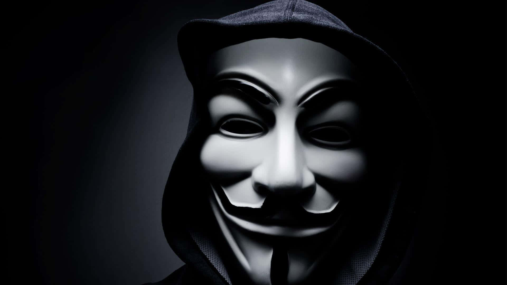 Anonymous 桌布 壁紙 — 一個穿著黑色連帽衫的人，在深色漸變背景前戴著白色蓋伊·福克斯面具。