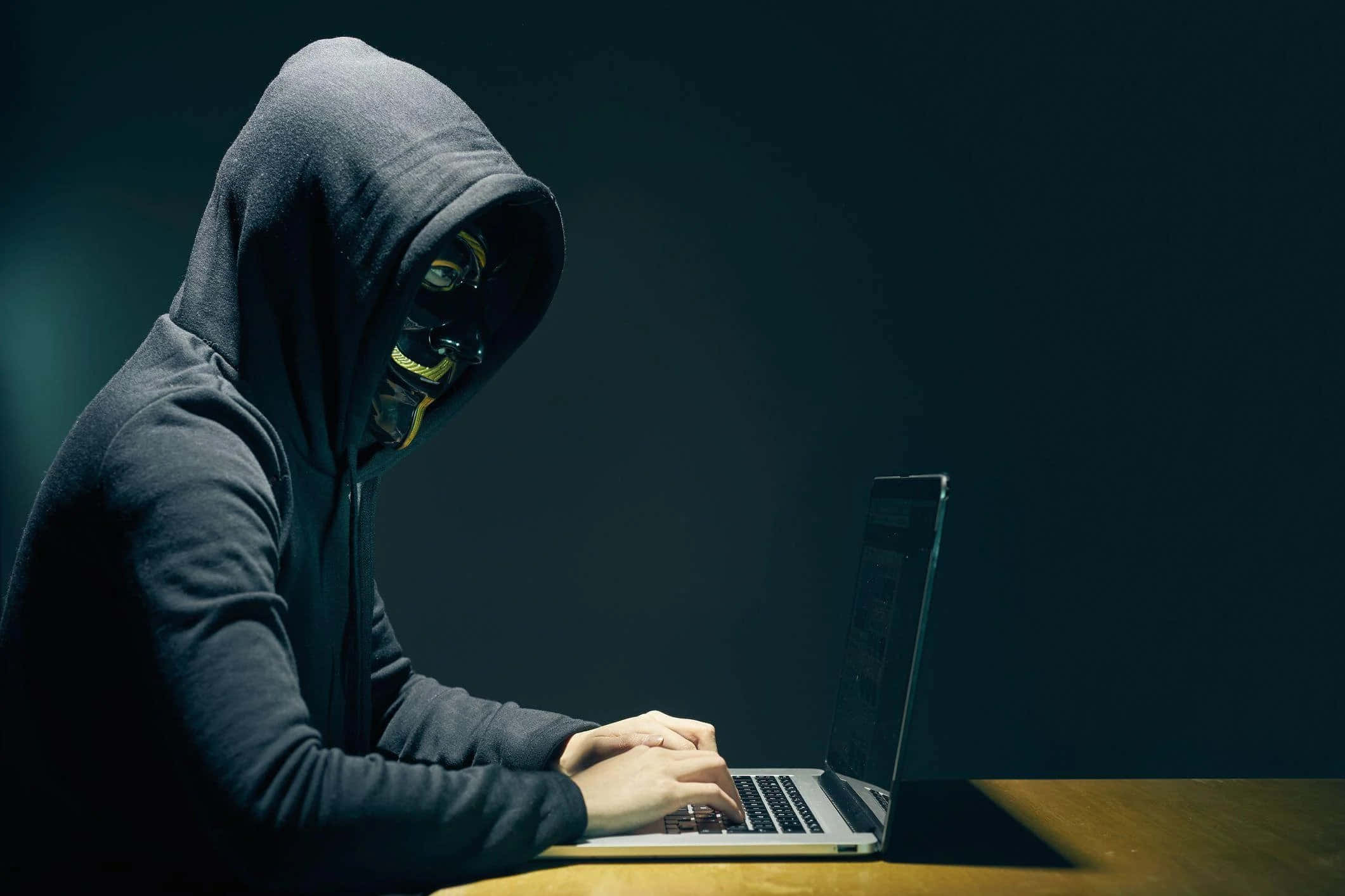一個穿連帽衛衣的男人正在使用手提電腦 壁紙