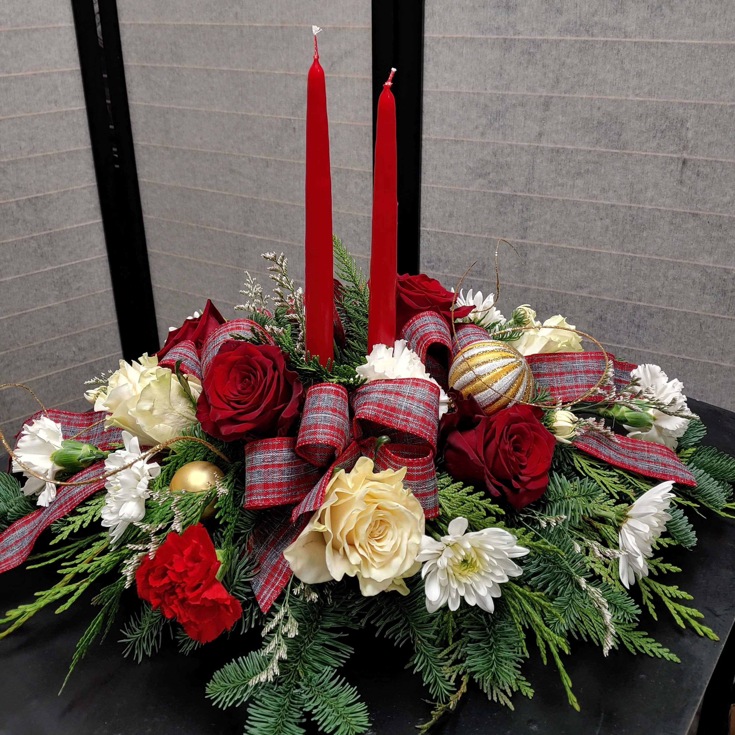 Centerpiece 桌布 壁紙 — 一個節日中心裝飾，在深色桌子上擺放紅色蠟燭、紅奶油色玫瑰、常綠枝條、格子絲帶和裝飾品。
