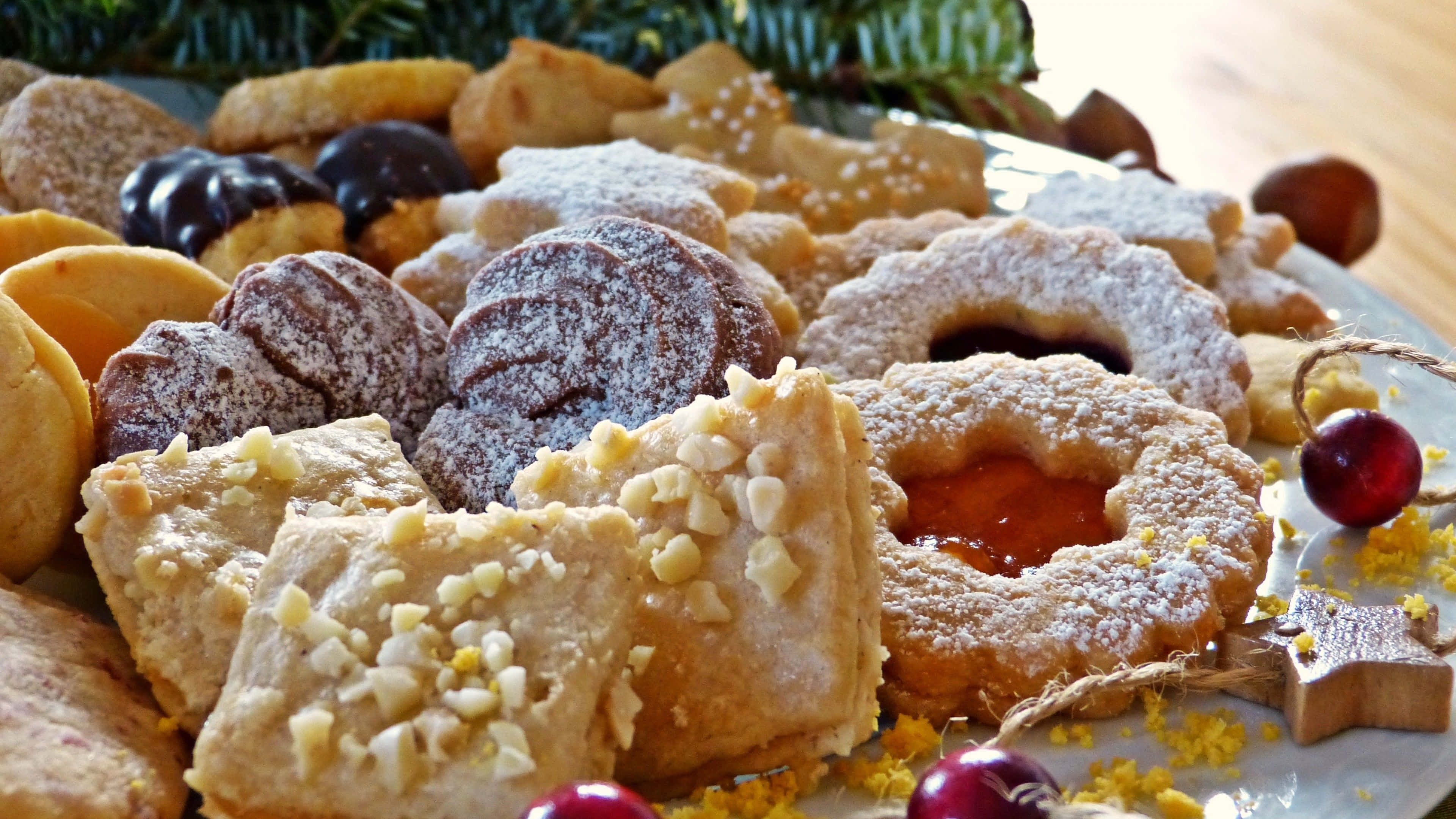 Pastry 桌布 壁紙 — 一個節日盤子，上面堆滿了各式各樣的節日餅乾，撒上糖粉，並用蔓越莓和松針裝飾。