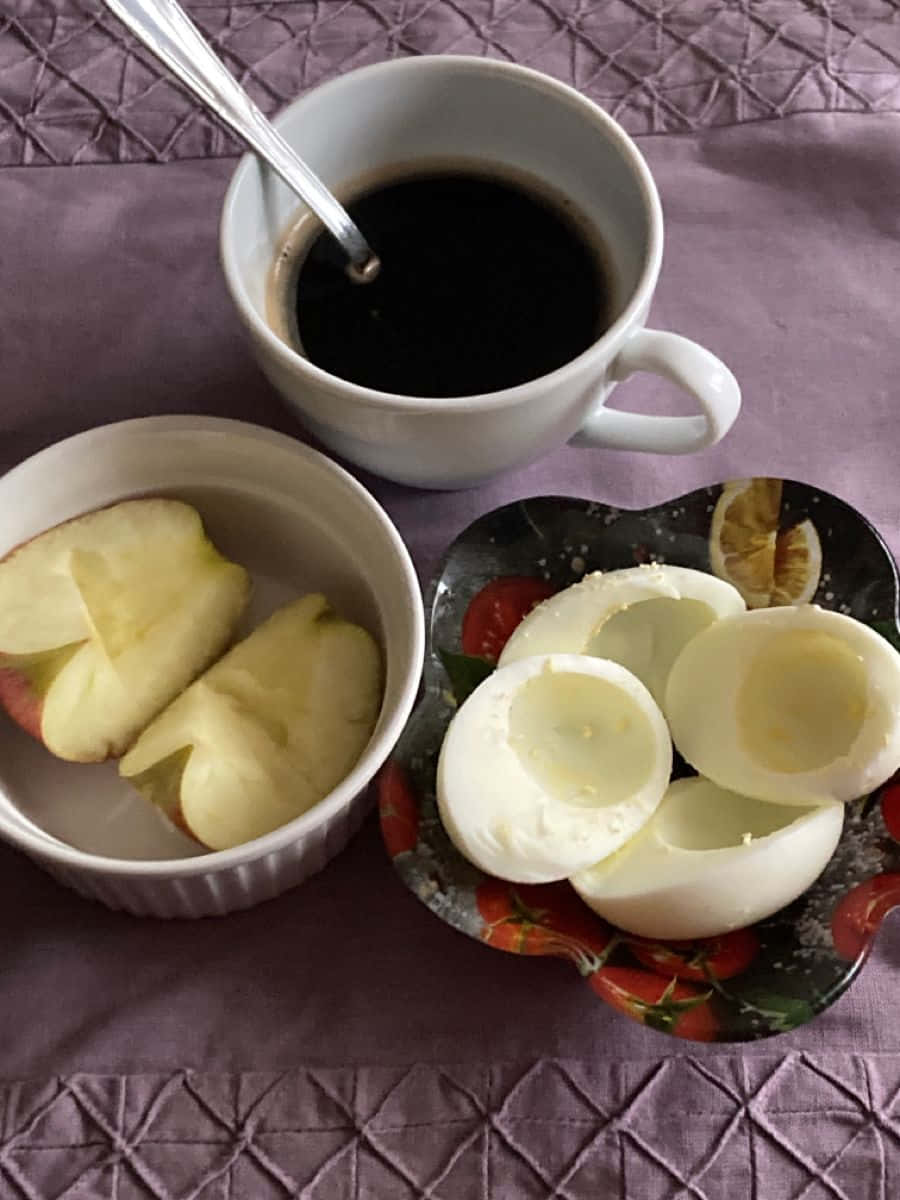 Minimalist Food 桌布 壁紙 — 一個簡單的早餐，包括咖啡、水煮蛋和蘋果片，放在紫色菱格紋桌布上。
