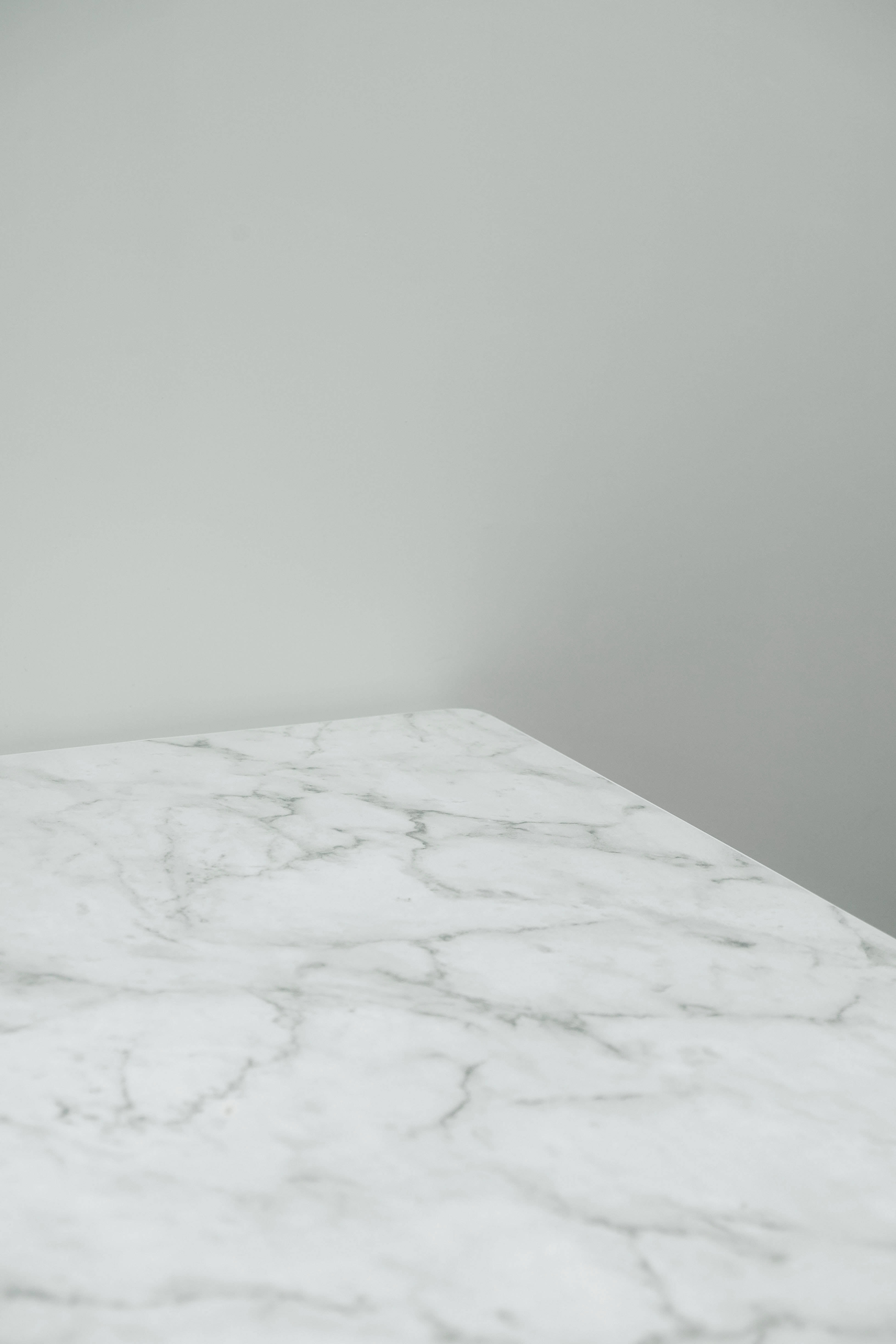White Marble 桌布 壁紙 — 一個簡約的白色大理石枱面，帶有灰色紋理，在乾淨的現代室內設計中與純灰色牆壁相遇。