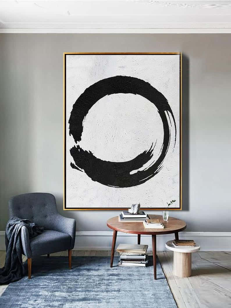 Modern Minimalist Art 桌布 壁紙 — 一個簡約風格的客廳，灰色牆上掛著一個大型裱框抽象黑色筆觸圓圈，下方是木桌和灰色扶手椅。