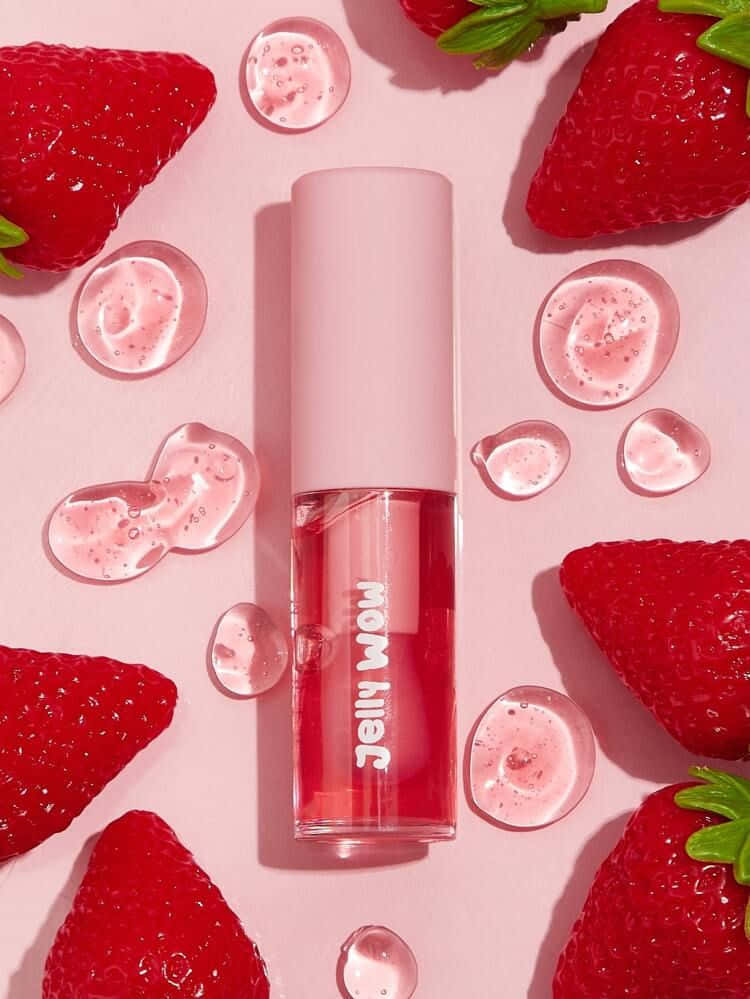 lipstick 桌布 壁紙 — 一個粉紅色唇彩瓶，周圍是新鮮草莓和閃爍的凝膠滴，背景是柔和的粉紅色。