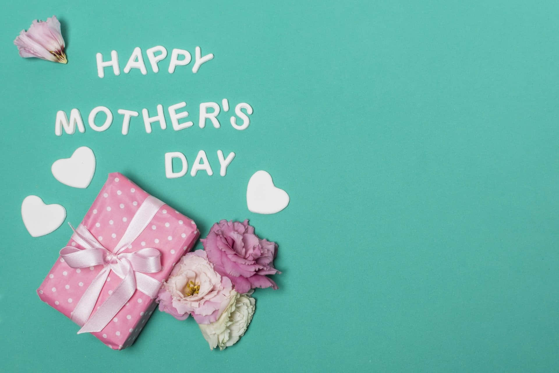 Happy Mothers Day 桌布 壁紙 — 一個粉紅色圓點禮物盒配上緞帶蝴蝶結，旁邊有粉紅玫瑰和白色心形，背景是青綠色，上面有白色字寫著「HAPPY MOTHER'S DAY」。