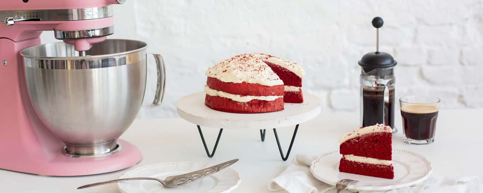 Red Velvet Cake 桌布 壁紙 — 一個粉紅色座枱攪拌機放在一個白色大理石架上，旁邊有一個紅絲絨蛋糕配忌廉芝士糖霜。