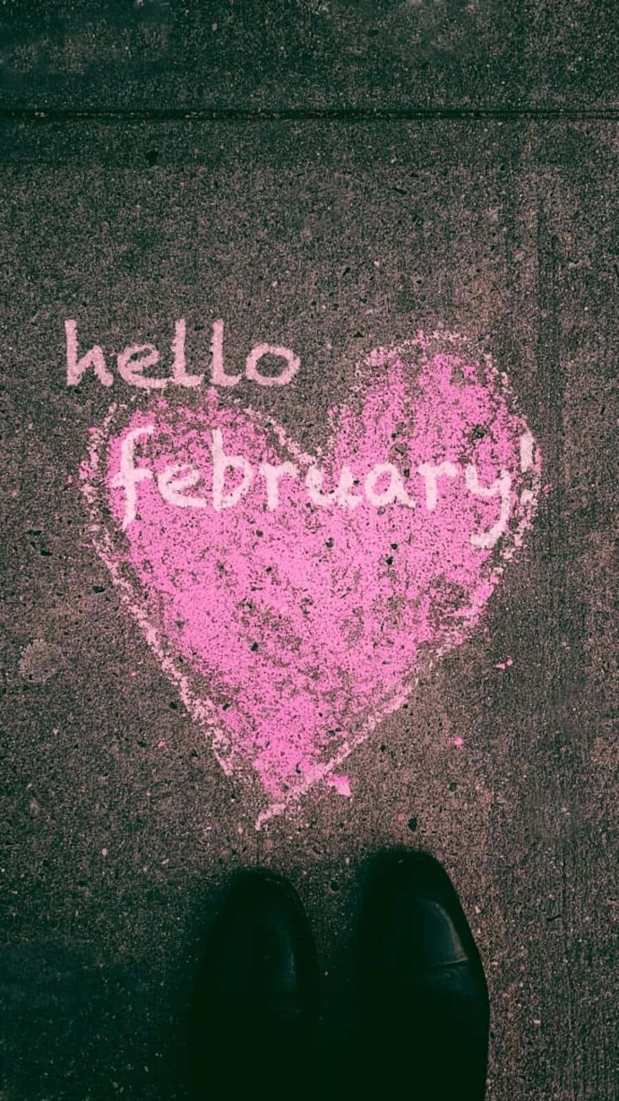 February iPhone 桌布 壁紙 — 一個粉紅色粉筆心形，裏面寫着hello february，在深色路面上，從上方俯瞰，底部有黑色鞋子。