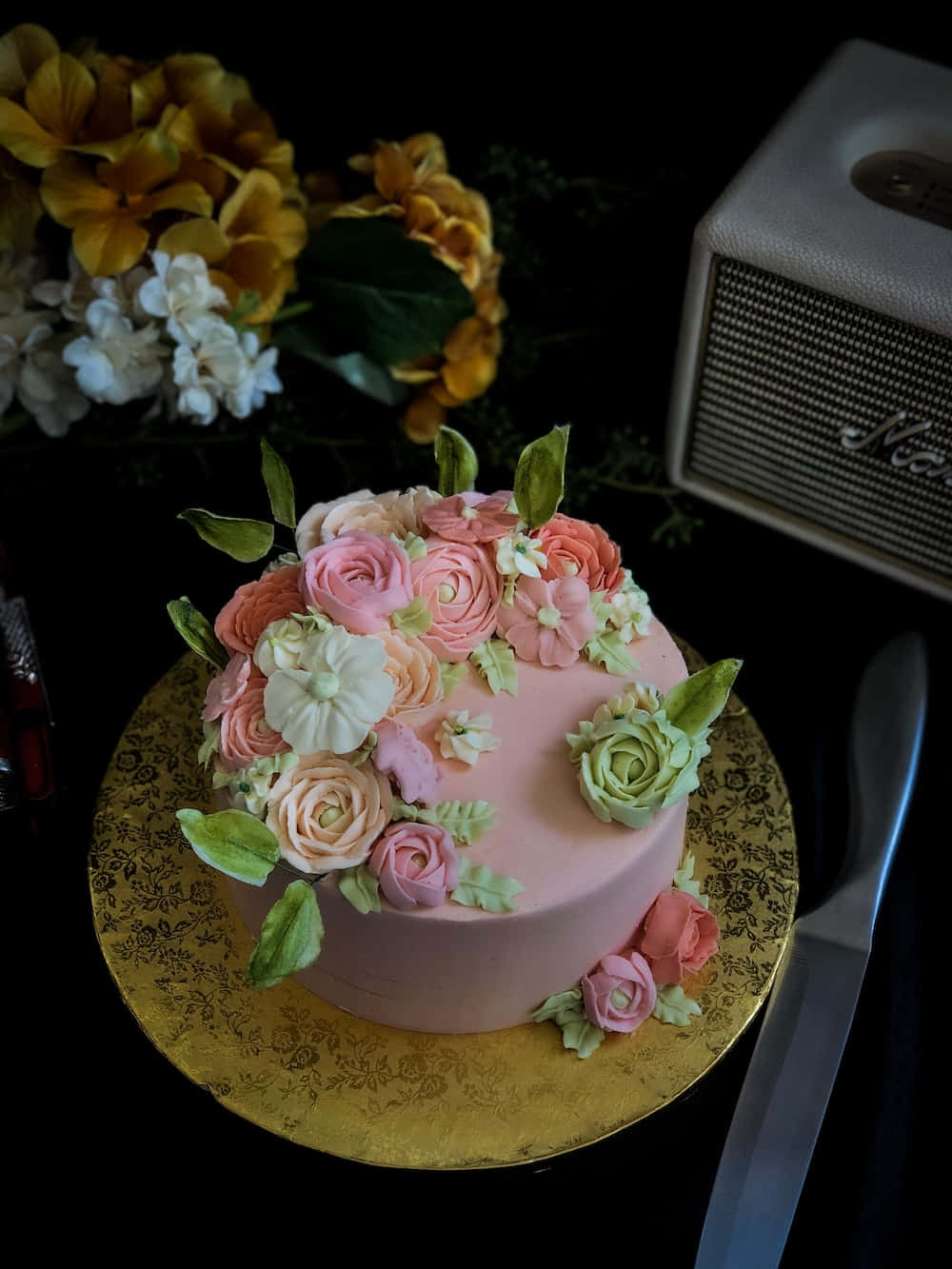 Floral Cake 桌布 壁紙 — 一個粉紅色蛋糕，飾有糖玫瑰和綠葉，放在金碟上，旁邊有一個復古揚聲器和鮮花。
