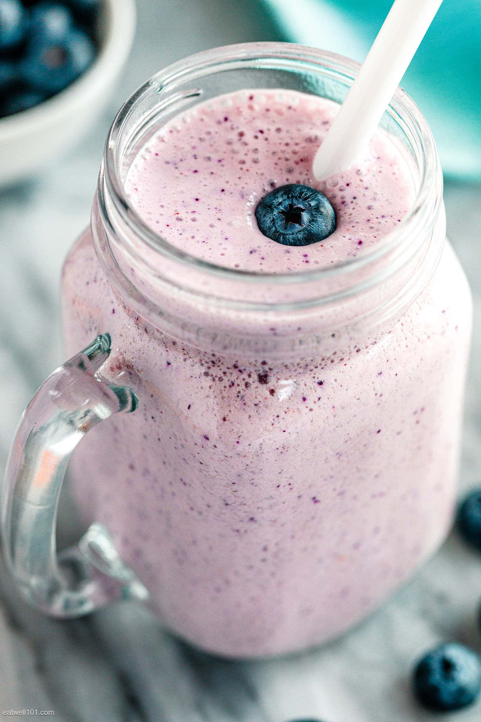 Blueberry Smoothie 桌布 壁紙 — 一個粉紅藍莓冰沙的特寫，裝在玻璃梅森罐中，上面放著新鮮藍莓和白色吸管。