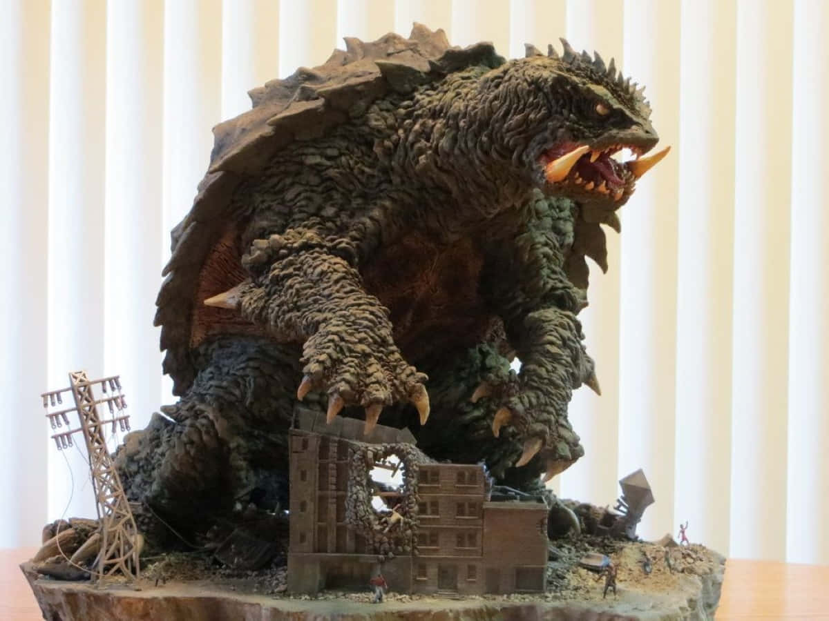 Gamera 桌布 壁紙 — 一個精細的哥斯拉雕像踩過一個微型毀滅城市景觀，有細小人物逃跑。