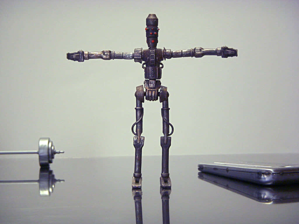 Ig-88 桌布 壁紙 — 一個精細的金屬機械人公仔站在反光表面上，雙臂伸展，旁邊有一個啞鈴和智能手機。