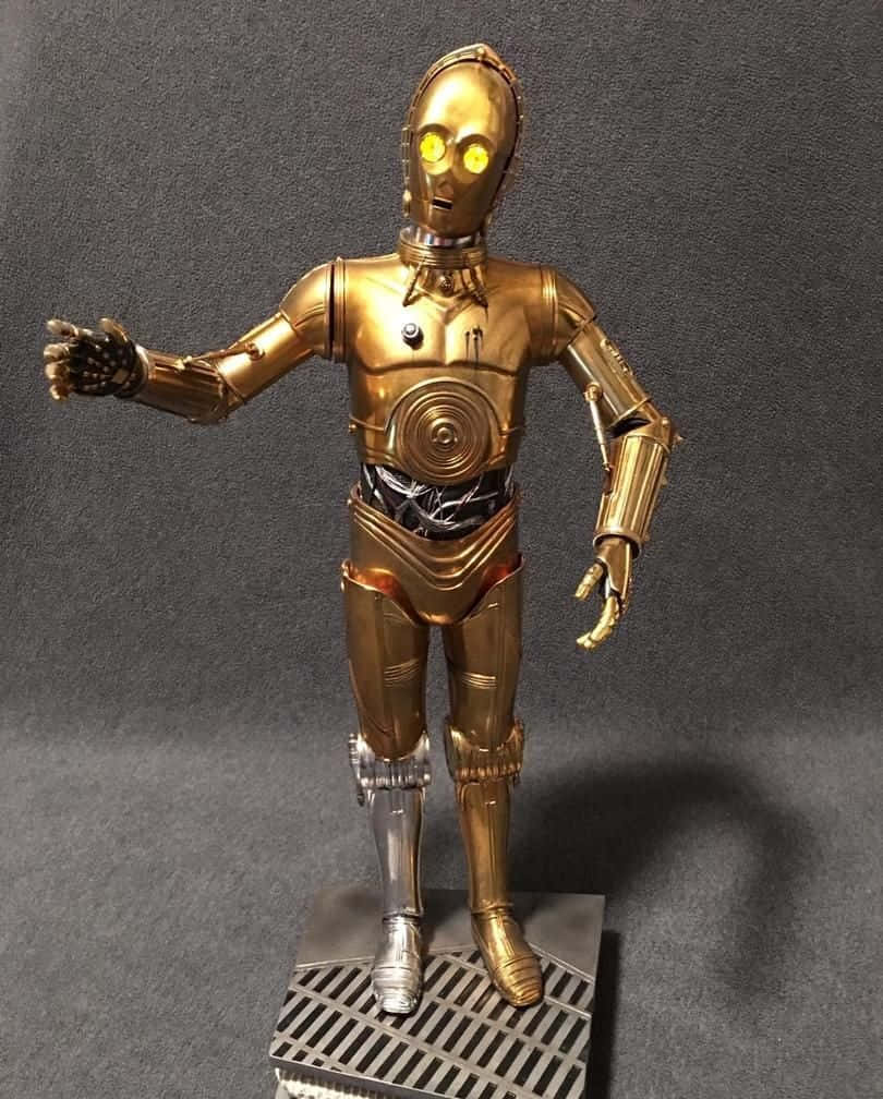 C-3po 桌布 壁紙 — 一個精細的金色c-3po動作人偶站在金屬底座上，黃色眼睛發光，背景為深灰色。