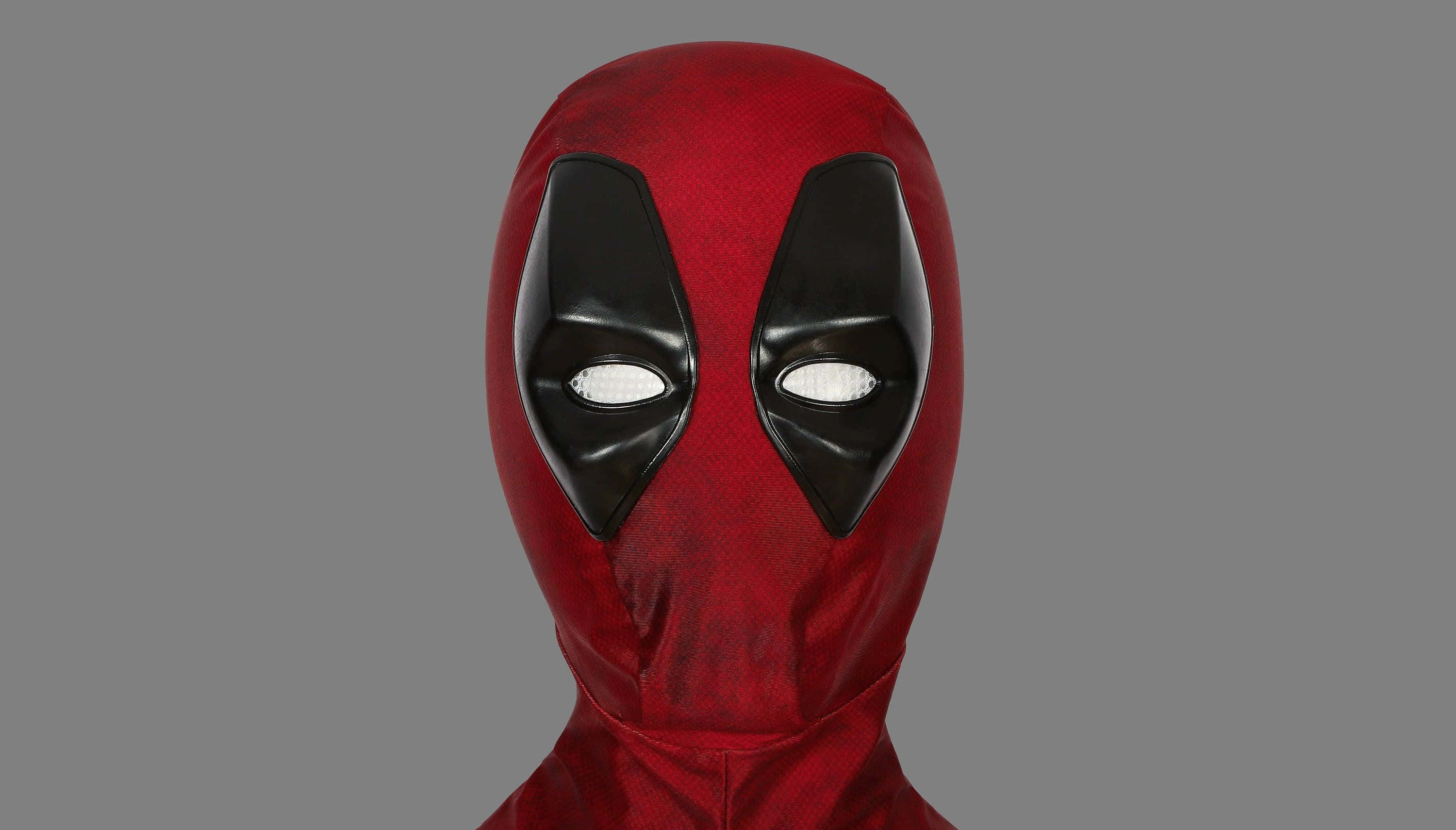 Deadpool Mask 桌布 壁紙 — 一個紅色和黑色的死侍面具特寫，白色眼睛，背景為純灰色。