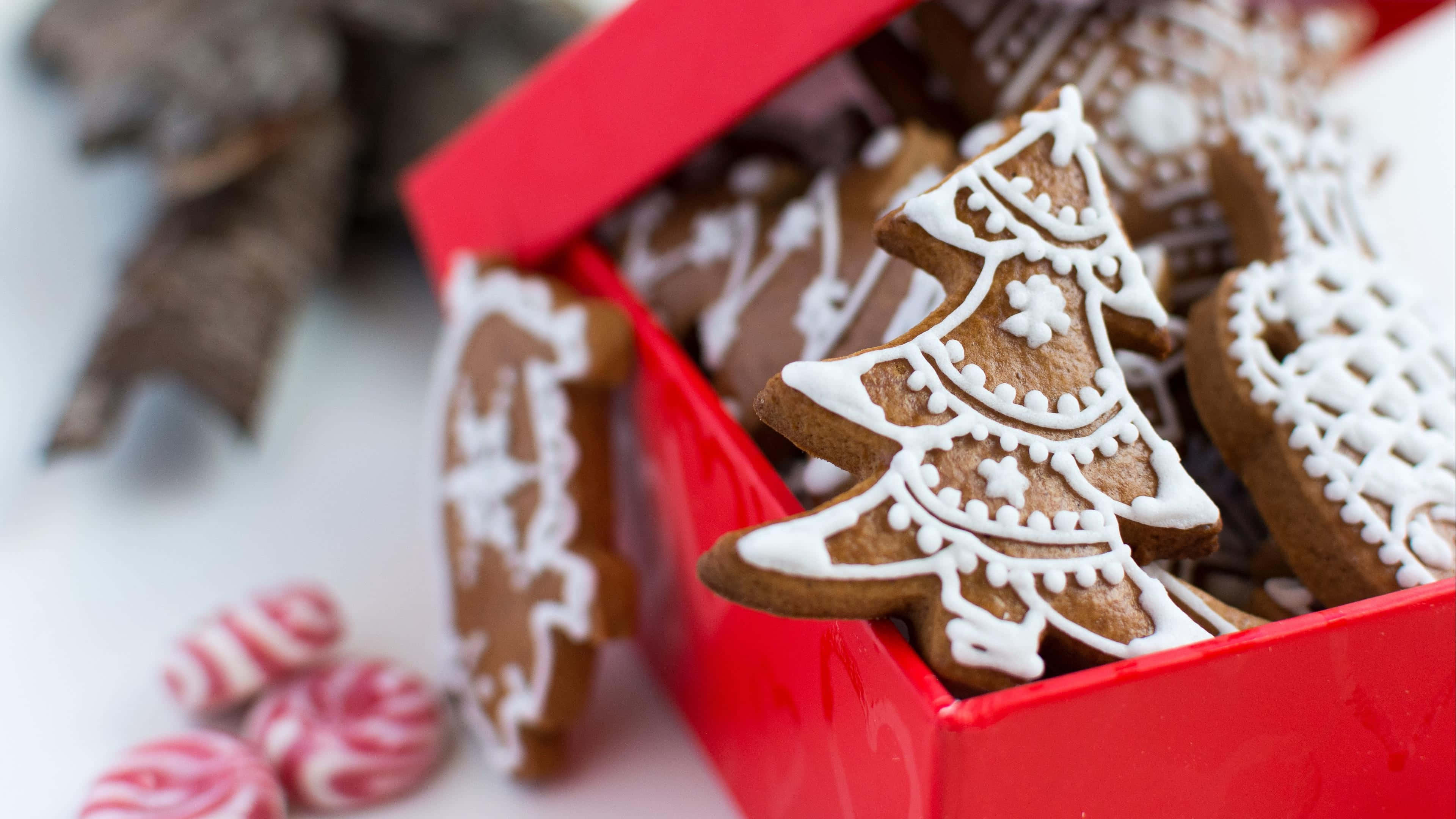 Gingerbread 桌布 壁紙 — 一個紅色盒子，裝滿了裝飾精美的薑餅聖誕樹曲奇和薄荷糖。