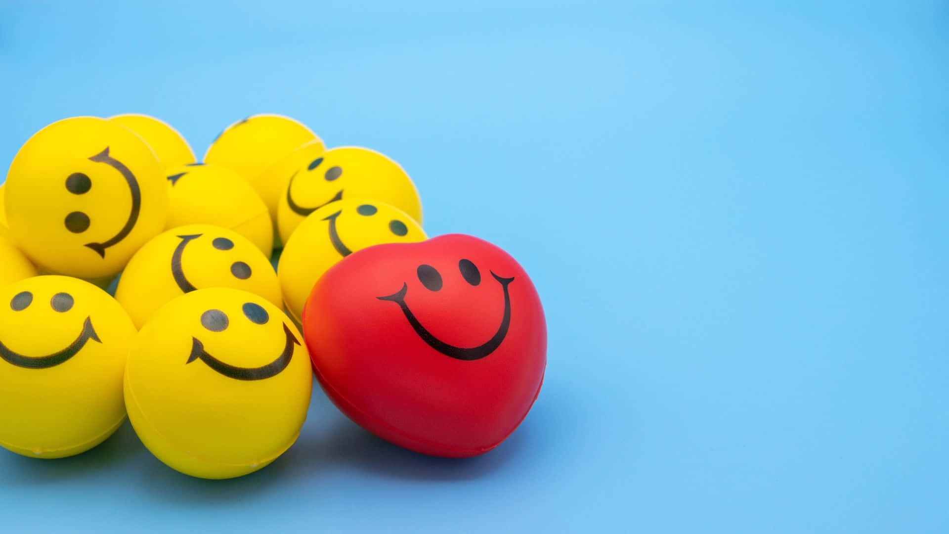Smiley 桌布 壁紙 — 一個紅色笑臉波在純藍色背景上的一堆黃色笑臉波中脫穎而出。