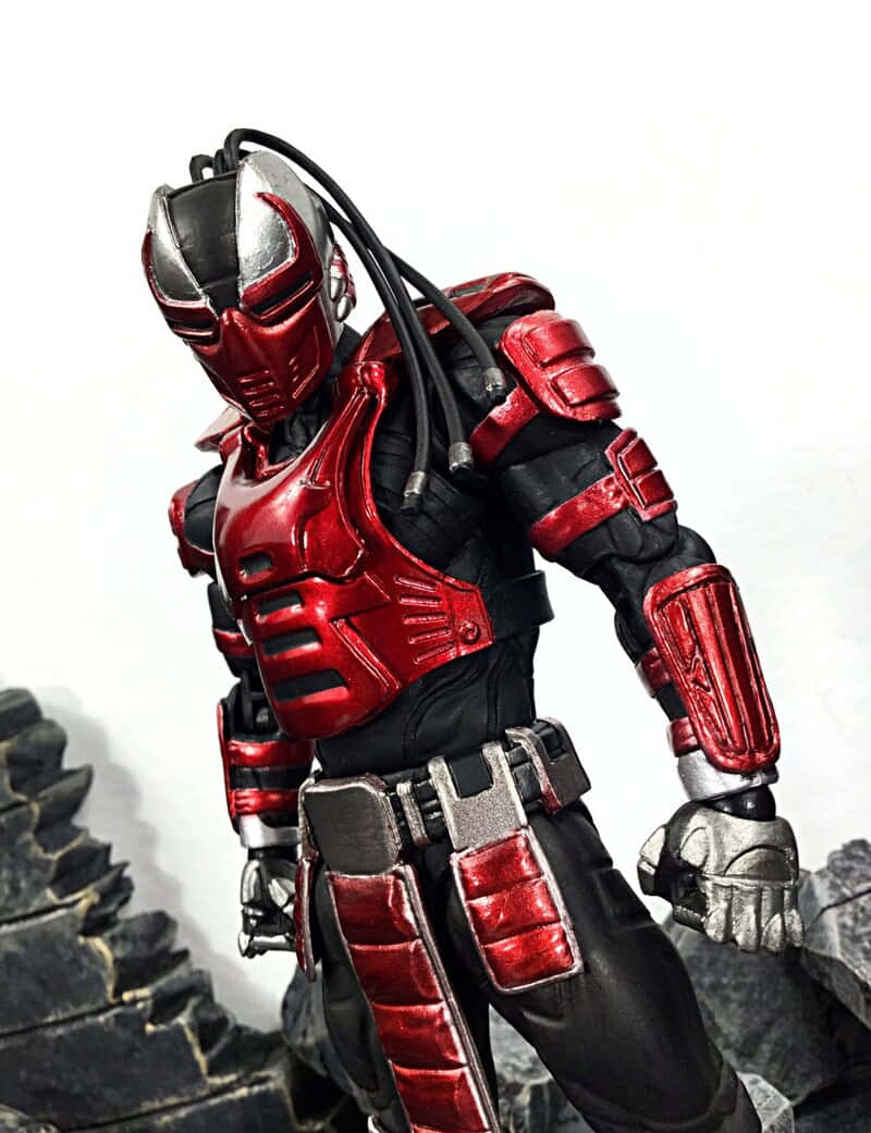 Mortal Kombat Sektor 桌布 壁紙 — 一個紅黑裝甲人物，戴著頭盔和連接線，站在岩石地形上，背景為純白色。