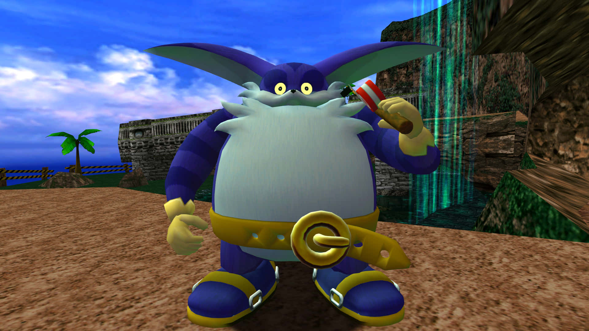 Big The Cat 桌布 壁紙 — 一個紫色兔仔角色，有白色鬍鬚同黃色腰帶，企喺沙灘上，附近有瀑布同棕櫚樹。