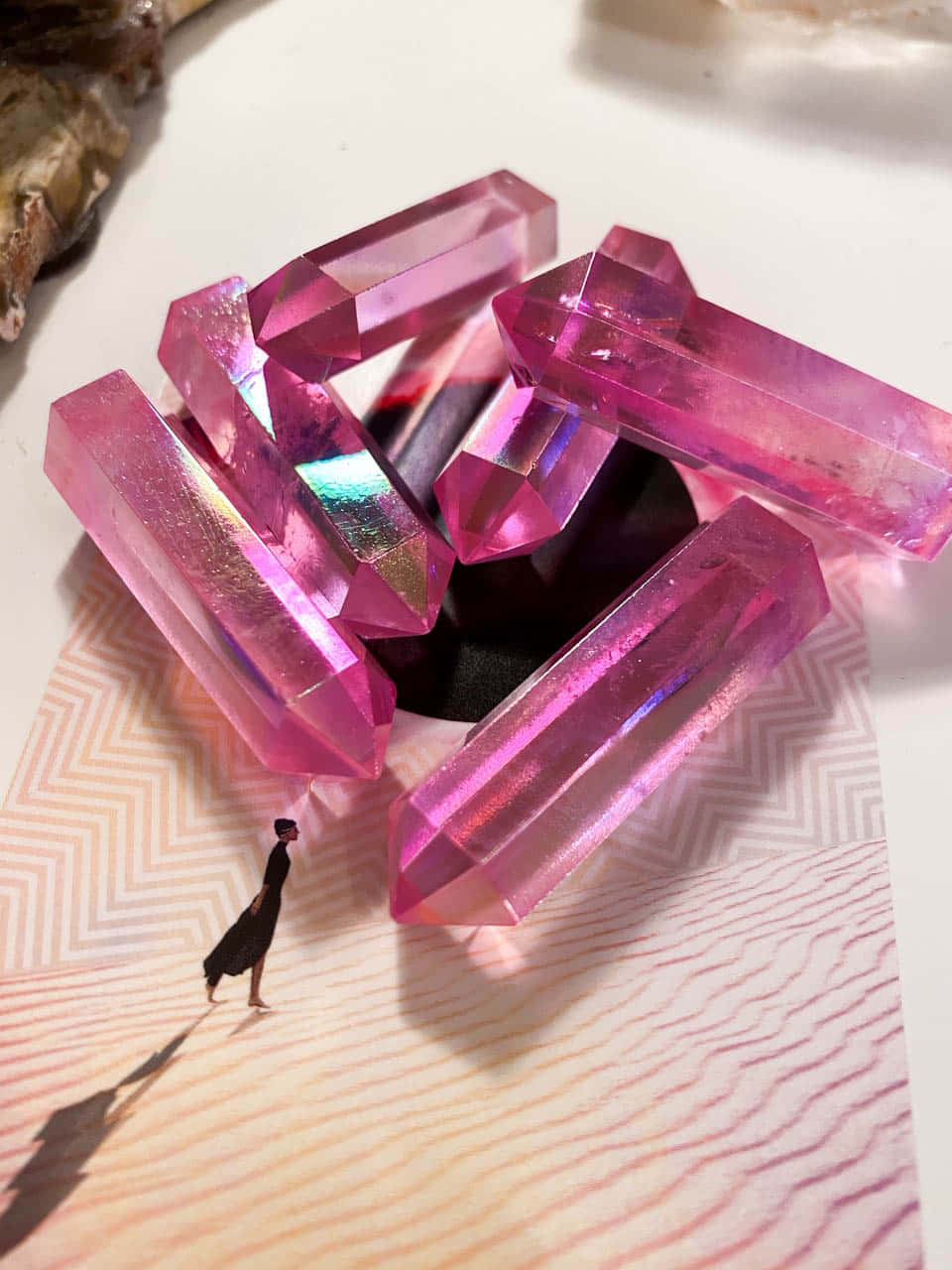 Pink Crystal Quartz 桌布 壁紙 — 一個細小嘅人物喺一個有圖案嘅表面上面，喺大型粉紅色水晶結構旁邊行，呢啲水晶結構投射出色彩繽紛嘅倒影。