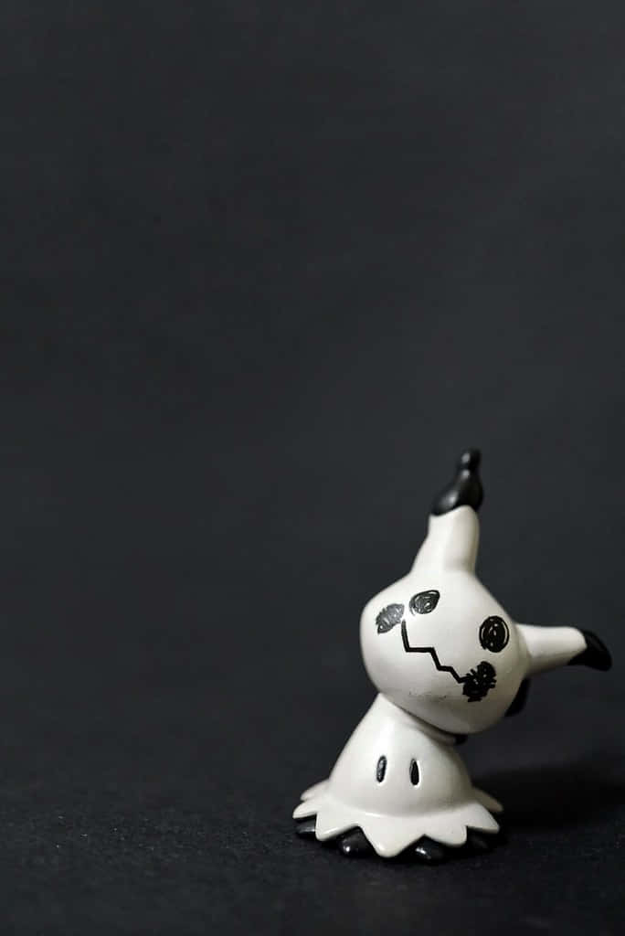 Pokemon Figures 桌布 壁紙 — 一個細小白色鬼魂般嘅寵物小精靈公仔，有黑色眼睛同鋸齒狀嘴巴，企喺深色紋理背景前面。