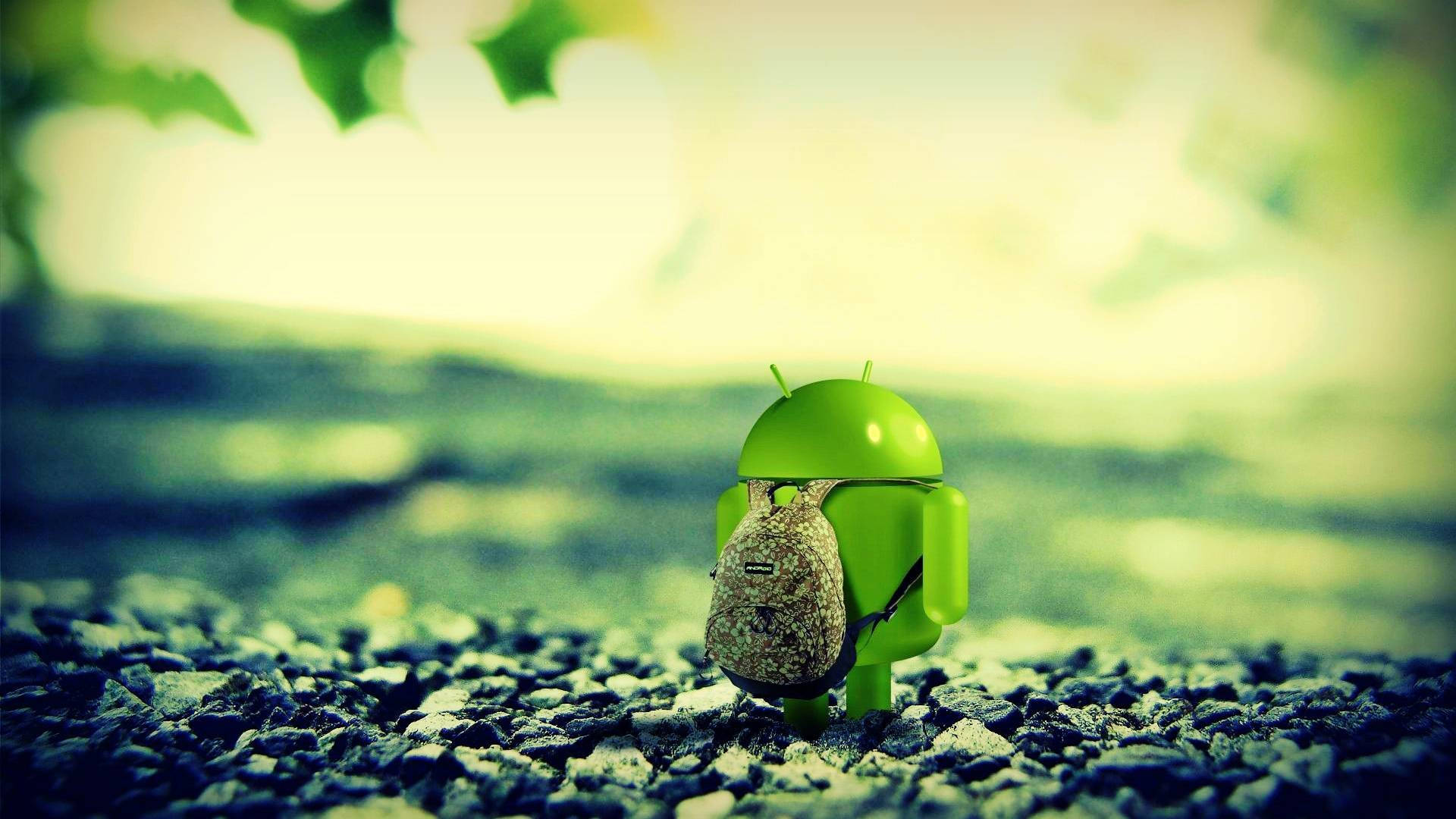 Full HD Tablet Android Robot 壁紙 — 一個細小的綠色Android公仔揹著背包，站在碎石路上，上方有柔和的陽光和模糊的樹葉。