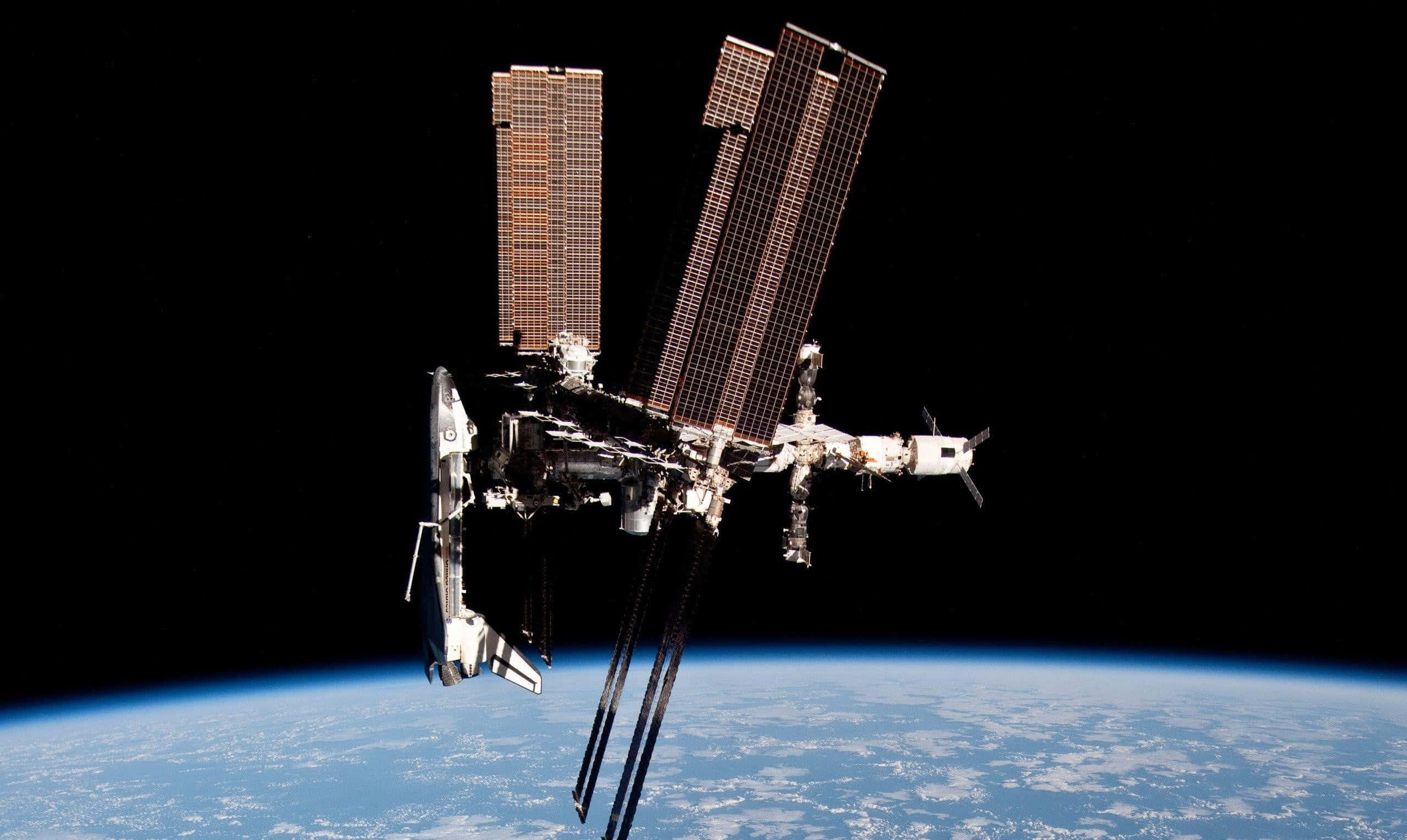 Satellite 桌布 壁紙 — 一個細節豐富的太空站，配備太陽能板，在太空的黑色虛空中繞著地球彎曲的藍色地平線運行。