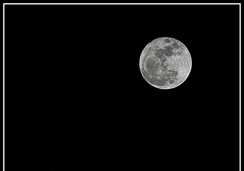 Perigee 桌布 壁紙 — 一個細節豐富的滿月，帶有隕石坑和月海，在漆黑的天空中發光，並以幼細的白色邊框框住。