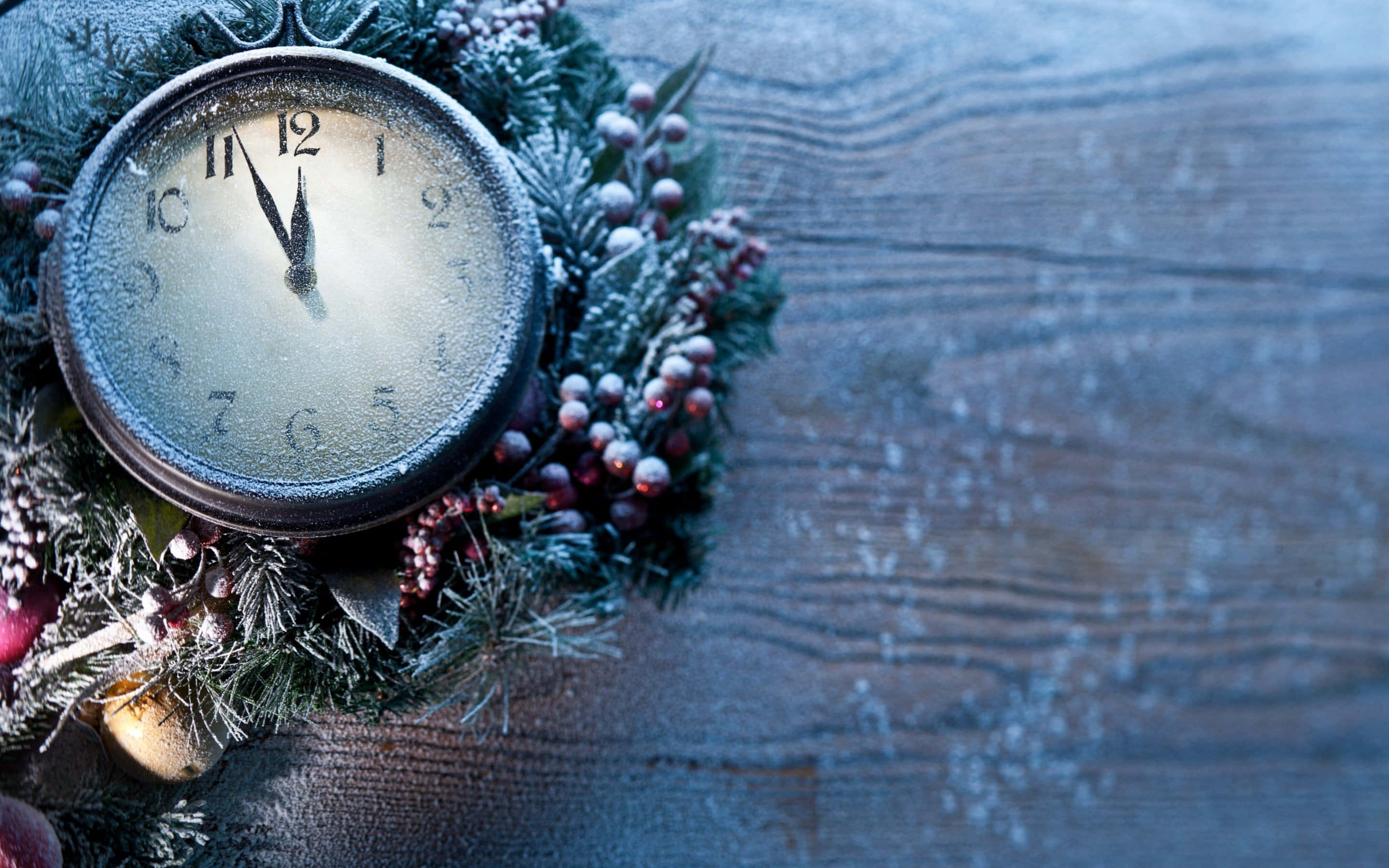 Time 桌布 壁紙 — 一個結霜的復古時鐘，藏在一個帶有漿果的雪地常綠花環中，放在一個風化的木質表面上。