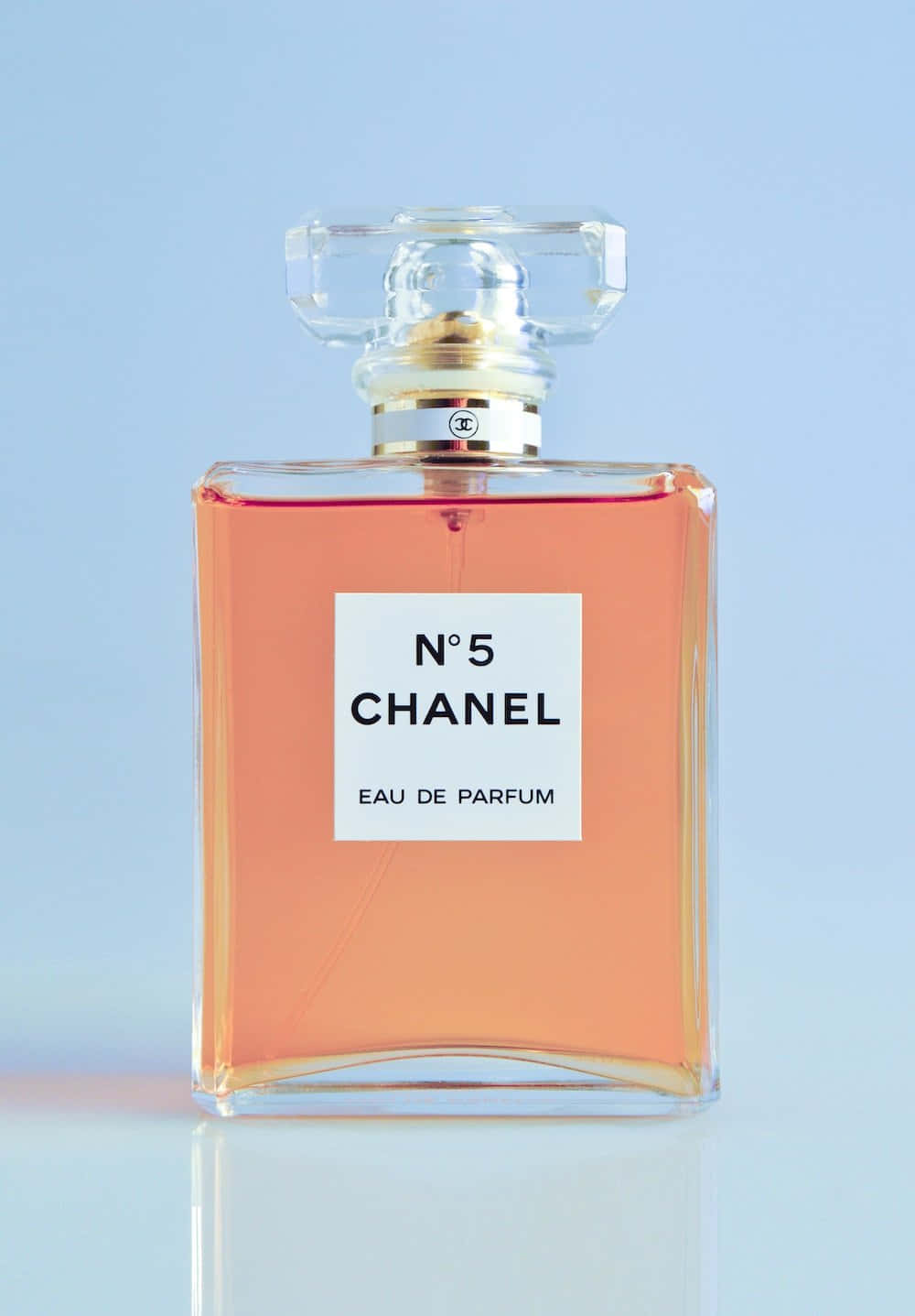 Spring Perfume 桌布 壁紙 — 一個經典的 Chanel No 5 香水瓶，裝有蜜桃色液體，置於柔和的藍色背景中央，帶有微妙的倒影。