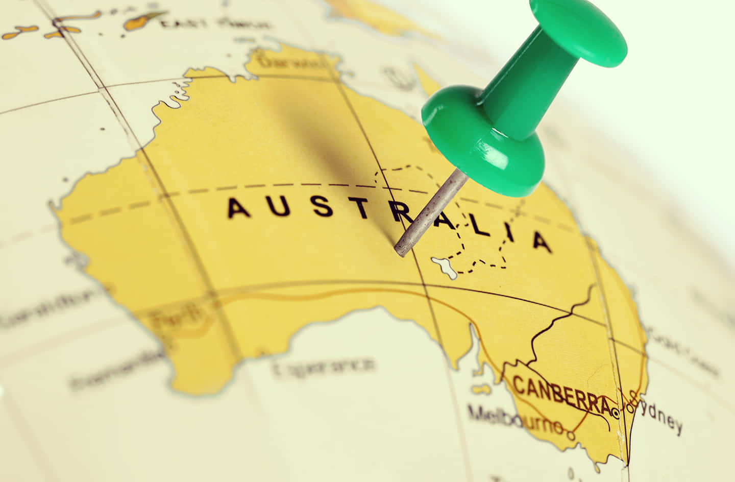 Australia 桌布 壁紙 — 一個綠色圖釘在詳細的黃色地圖上標記澳洲，地圖上可見坎培拉和悉尼等城市。