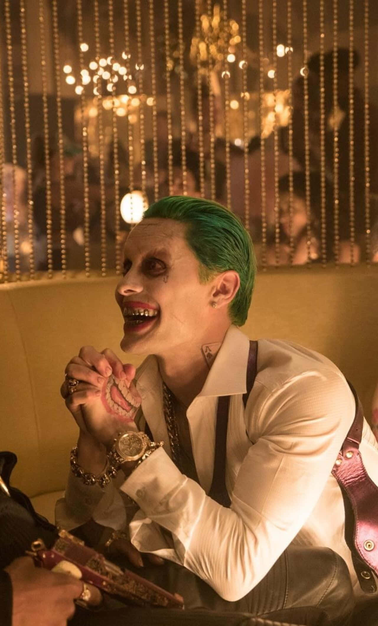 Suicide Squad 桌布 壁紙 — 一個綠髮白臉的男人在金碧輝煌的休息室裡，掛著珠簾和水晶吊燈，狂笑著。