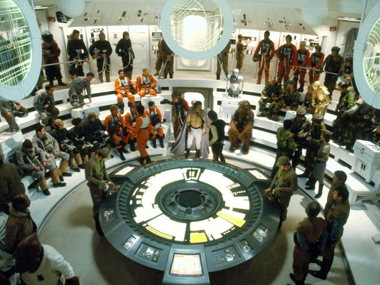 The Battle Of Endor 桌布 壁紙 — 一個繁忙的太空船艦橋，充滿了穿著橙色和灰色制服的多樣化船員，聚集在一個發光的中央控制面板周圍。