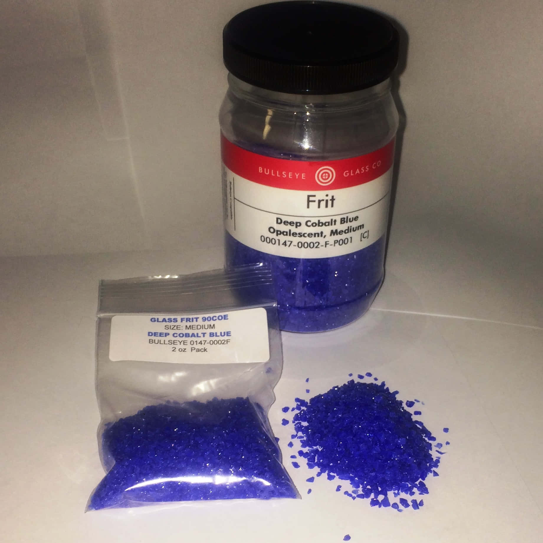 Cobalt Blue 桌布 壁紙 — 一個罐子和袋子裝有深鈷藍色乳白玻璃熔塊，有些灑落在白色表面上。