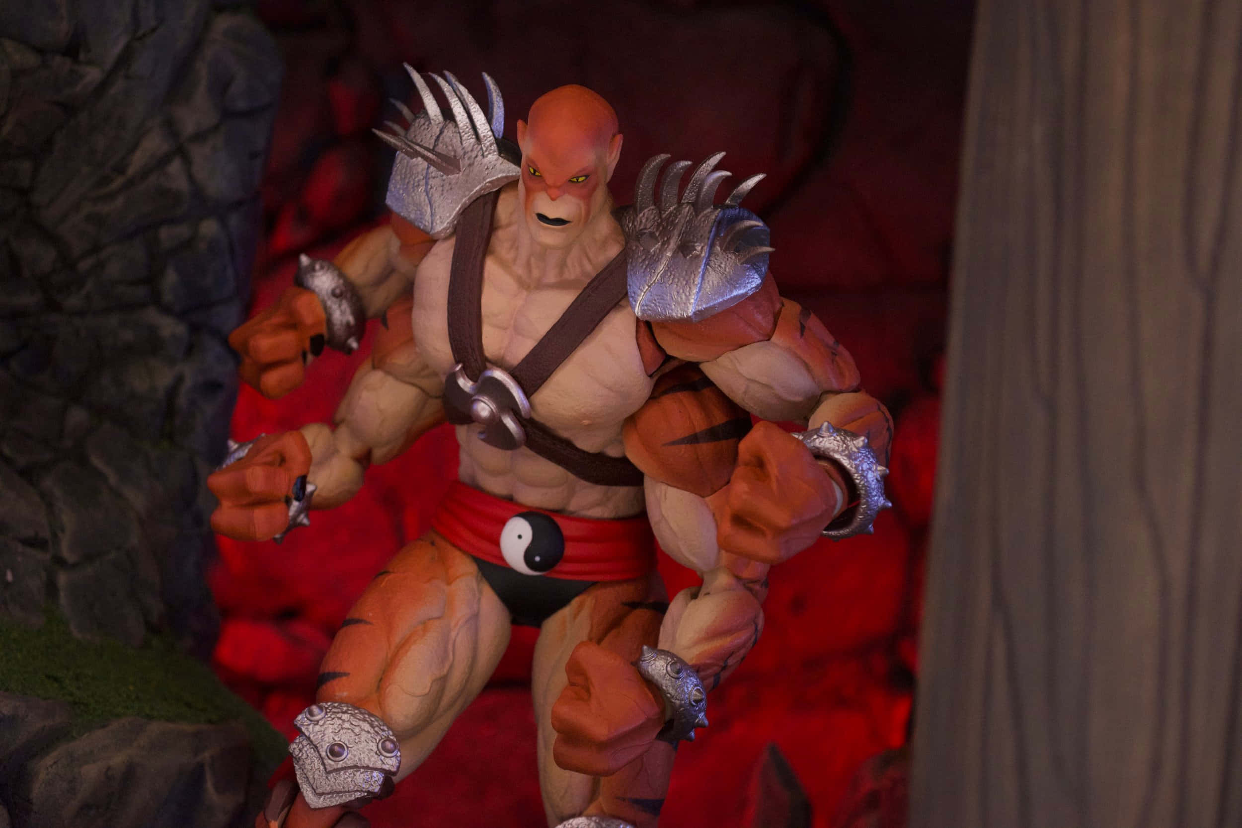 Mortal Kombat Kintaro 桌布 壁紙 — 一個肌肉發達、紅色皮膚的戰士，戴著銀色爪套，站在一個岩石洞穴中，身後是發光的紅色熔岩。