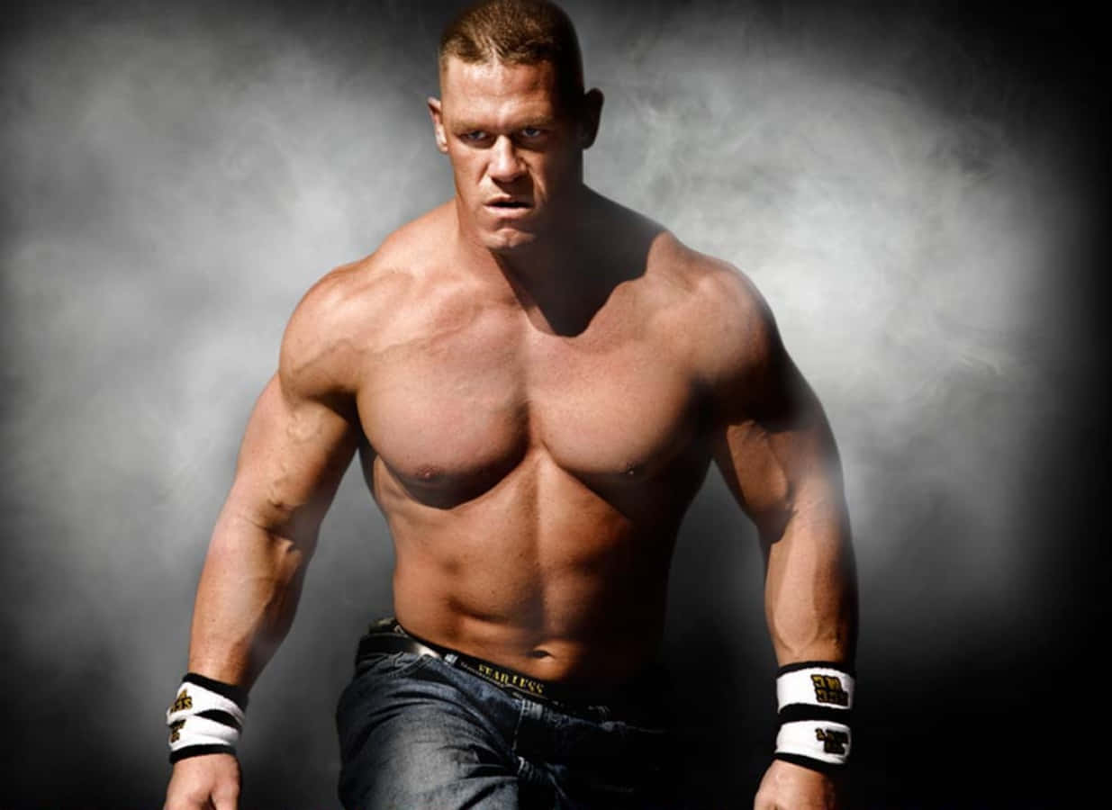 John Cena 桌布 壁紙 — 一個肌肉發達、腹肌分明、眼神銳利的男人，赤裸上身站在煙霧瀰漫的黑暗背景前。