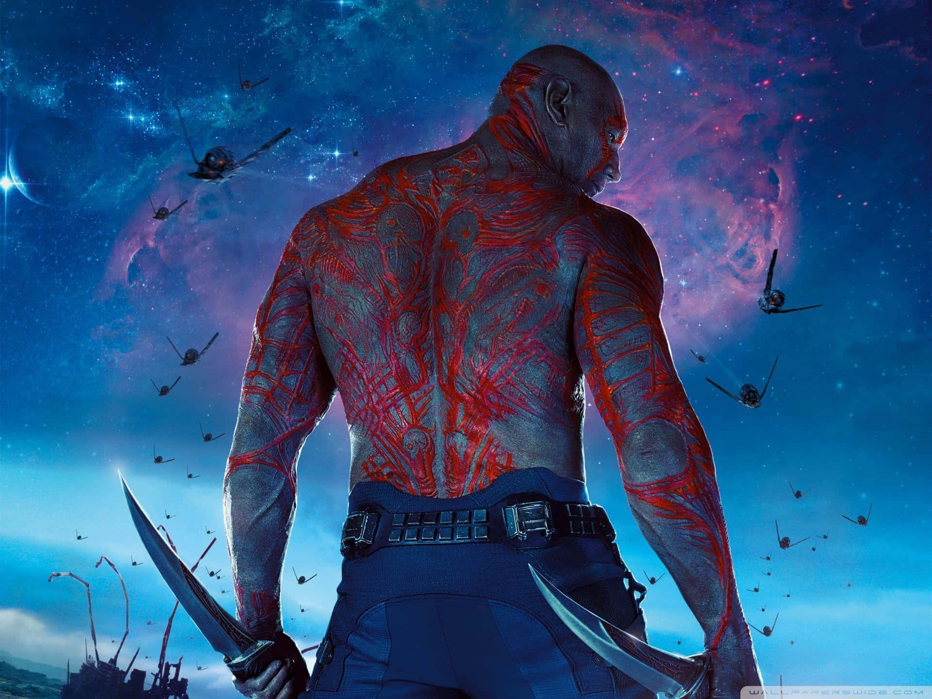 Drax 桌布 壁紙 — 一個肌肉發達的光頭男子，身上有紅色紋身，背對宇宙星雲，手持雙刃，太空船飛過。
