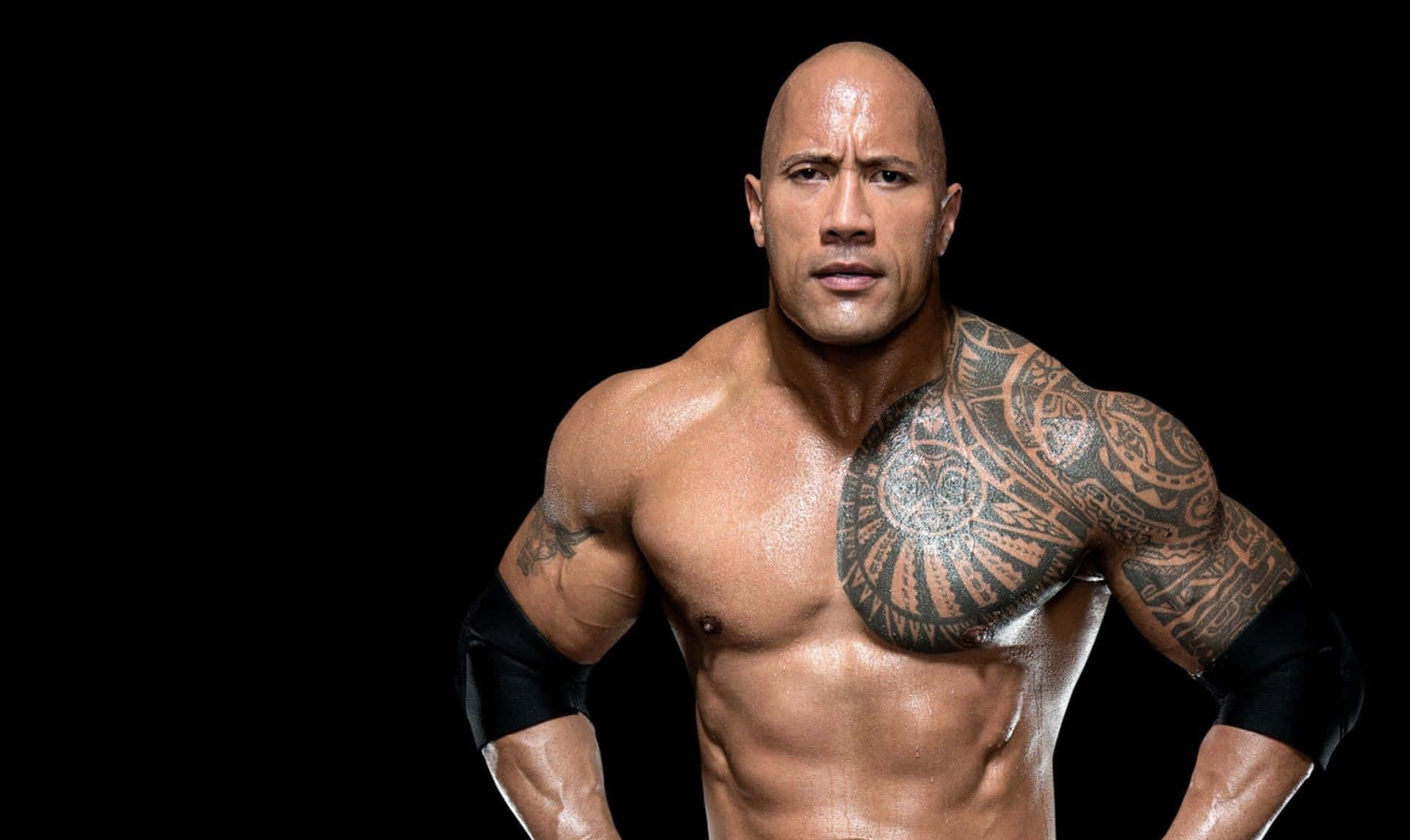 The Rock 桌布 壁紙 — 一個肌肉發達的光頭男子，身上有部落紋身，在黑色背景下強烈地凝視。