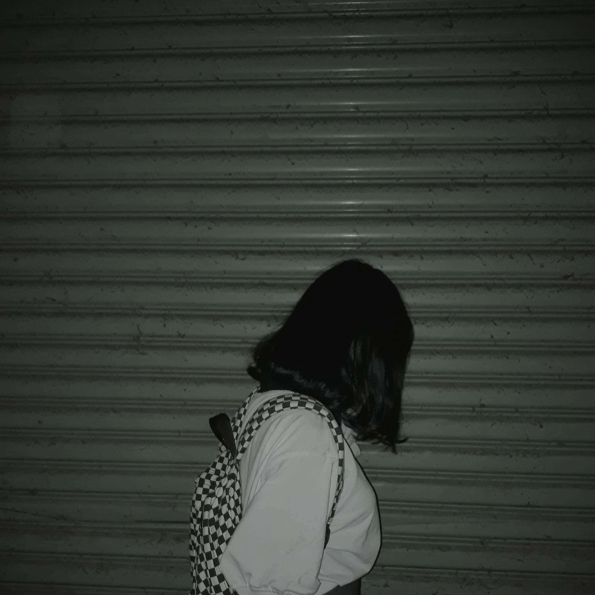 一個背著背包的女人站在車庫前 壁紙