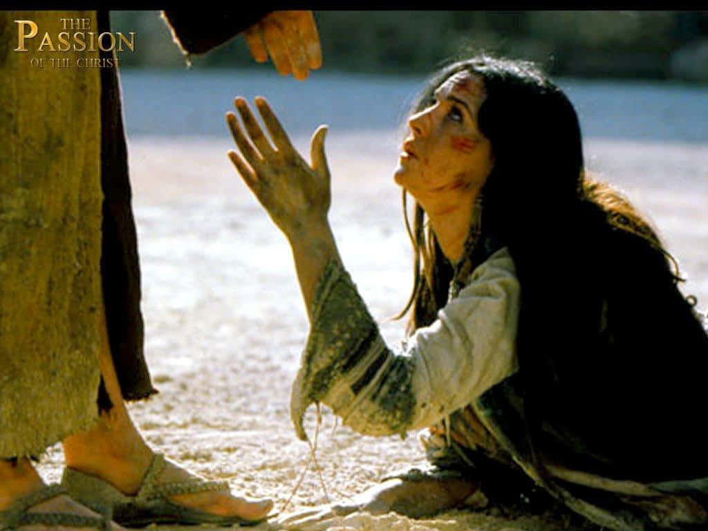 Mary Magdalene 桌布 壁紙 — 一個臉上沾滿泥土和血的女人跪在沙地上，伸手向一個聖經場景中的高聳人物。