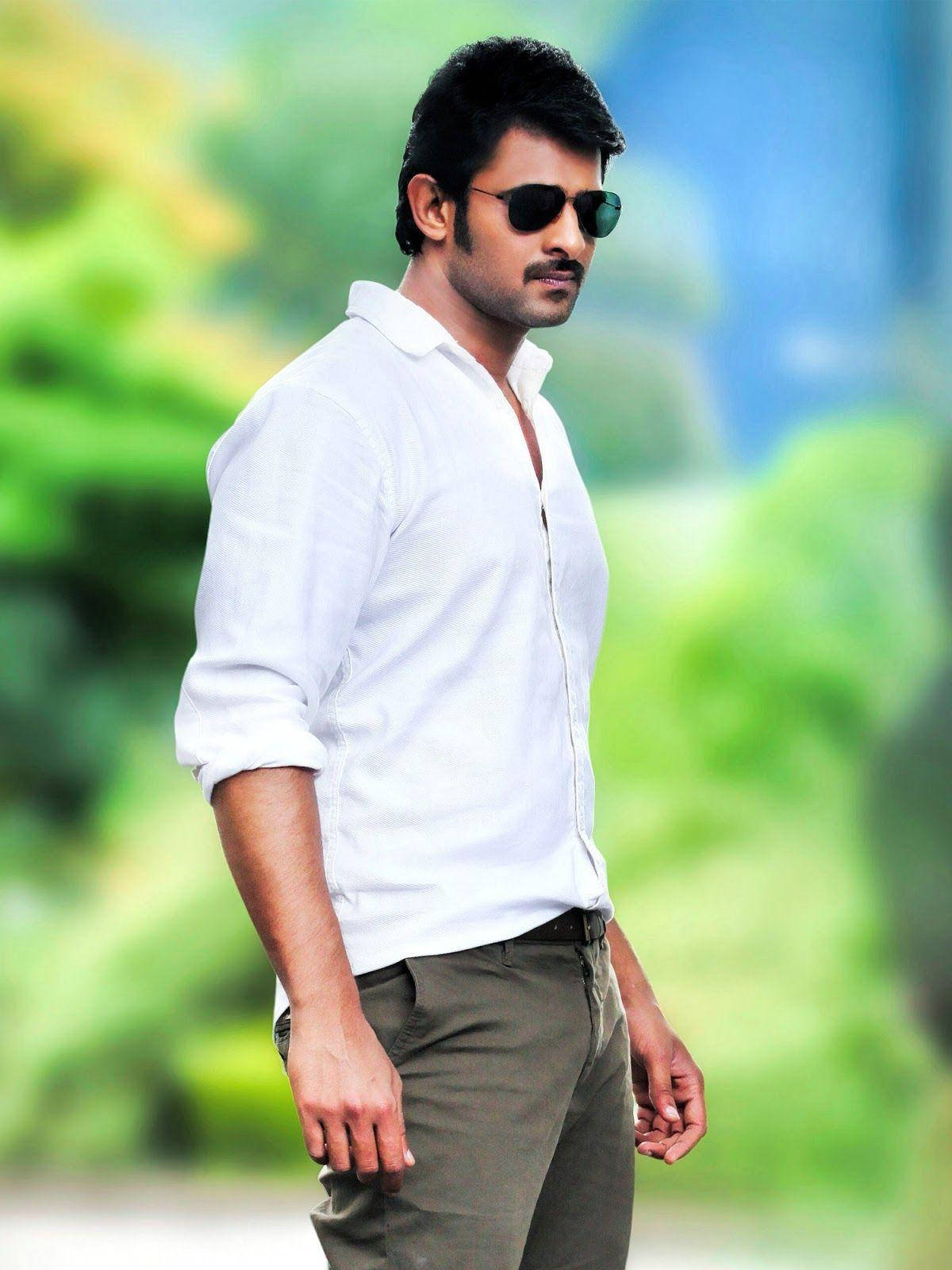 Prabhas Mirchi 桌布 壁紙 — 一個自信嘅男人，著住白恤衫同太陽眼鏡，企喺充滿活力嘅綠色模糊背景前面。