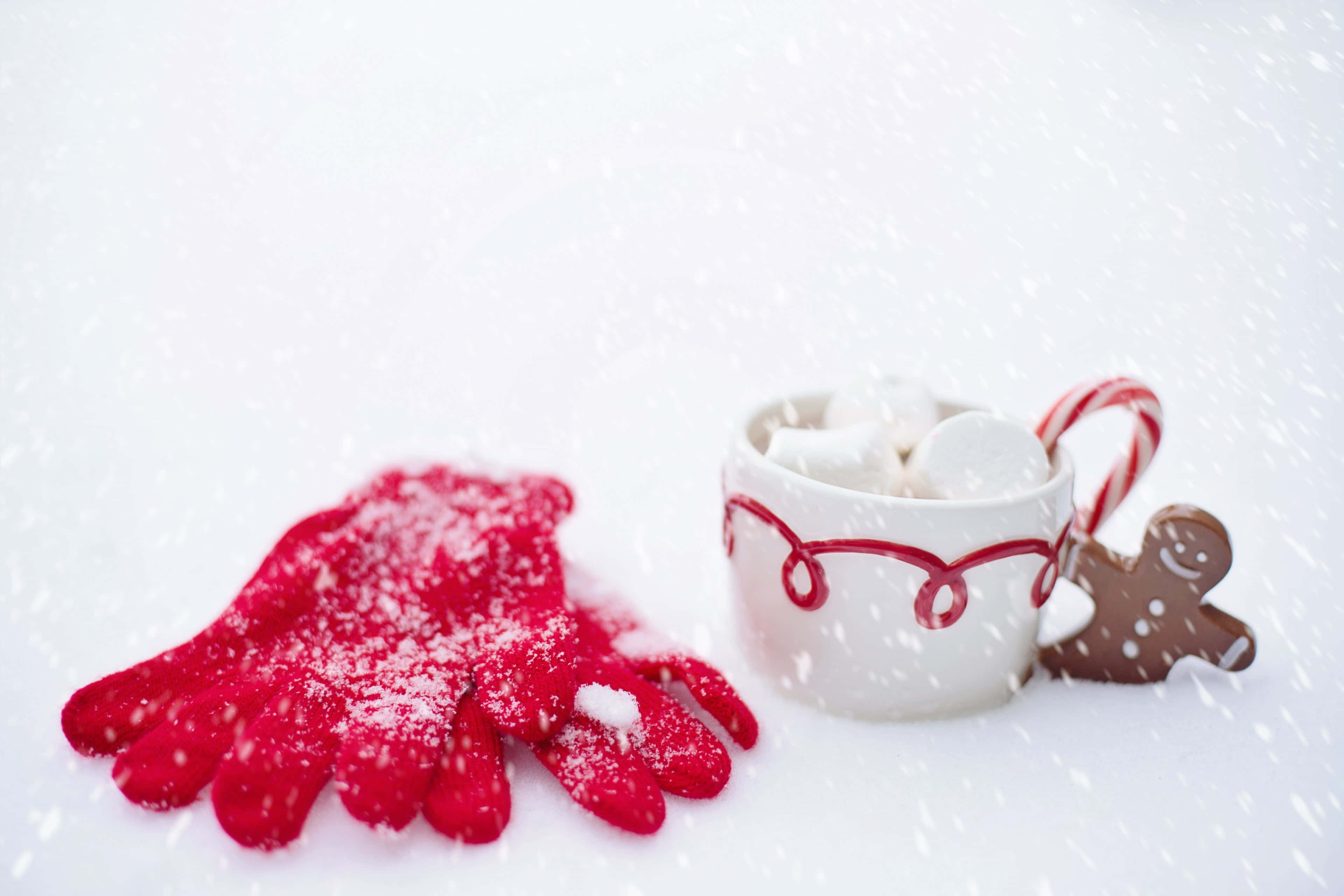 Hot Chocolate 桌布 壁紙 — 一個舒適的冬日場景，有紅色手套、雪花、一杯熱可可、棉花糖和一個薑餅人。