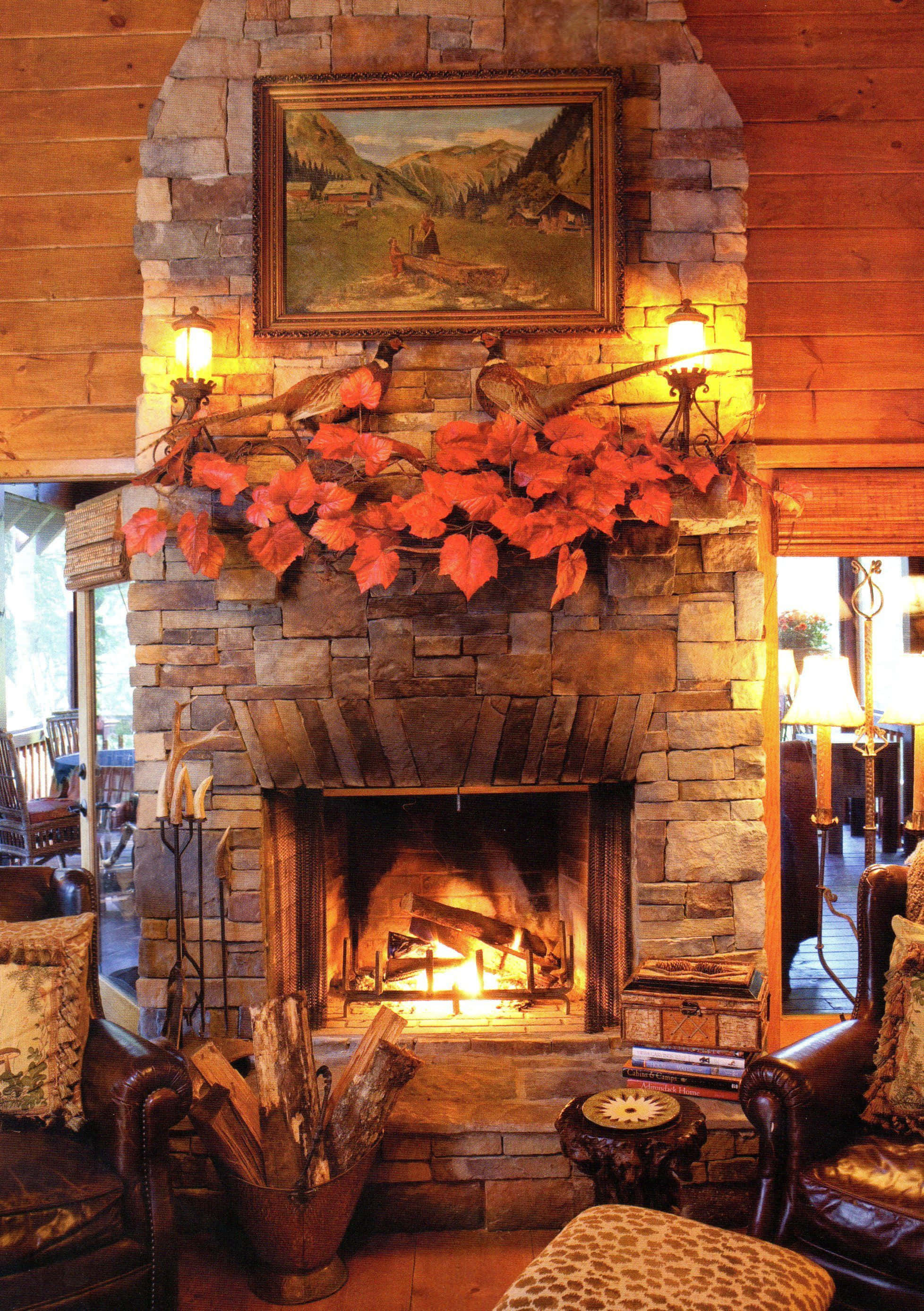 Autumn Fireplace 桌布 壁紙 — 一個舒適的石壁爐噼啪作響，溫暖的火焰中點綴著鮮豔的紅色秋葉和質樸的木質裝飾，位於木鑲板的小屋中。