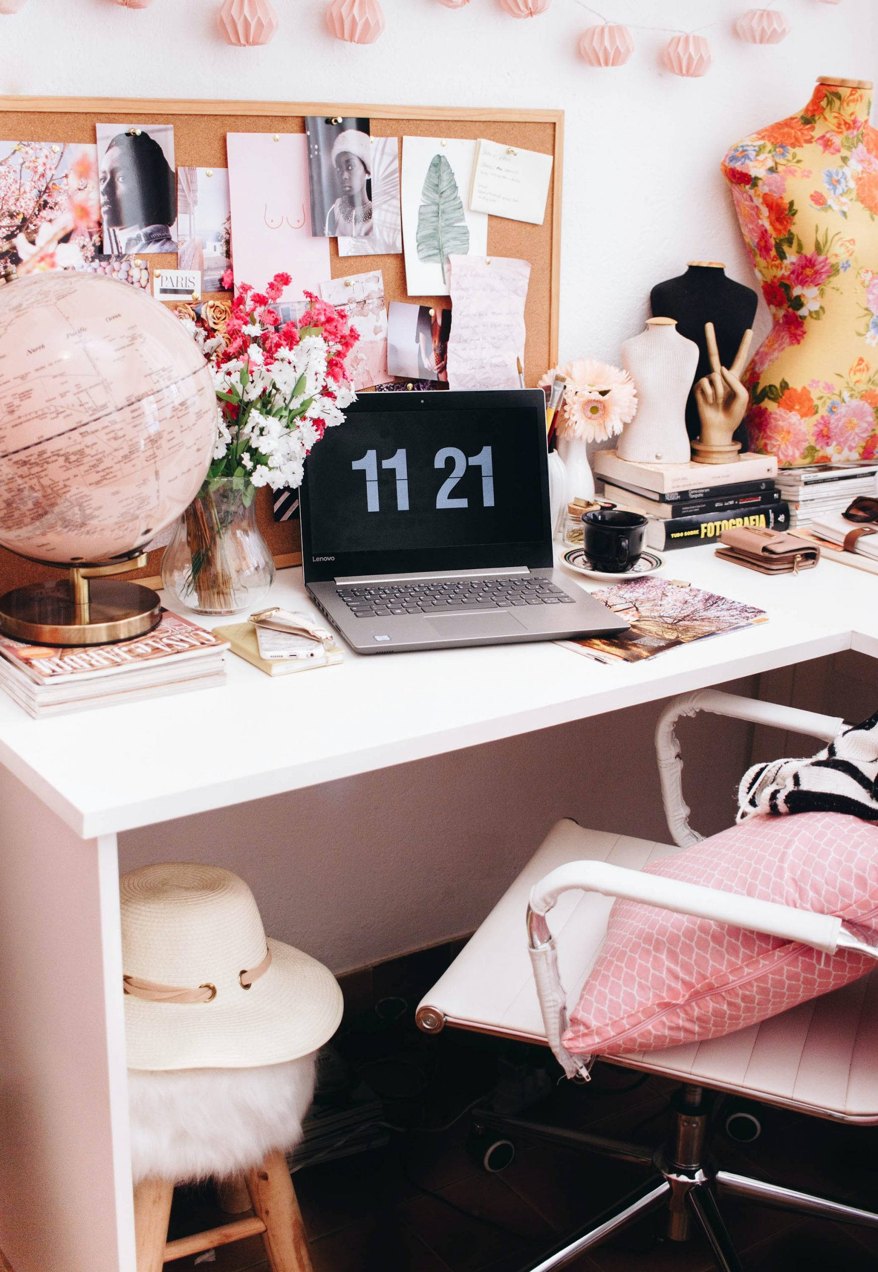 Working From Home 桌布 壁紙 — 一個舒適的粉紅色主題家居辦公室書桌，配有筆記型電腦、地球儀、鮮花和人體模型，在溫暖的燈光下。