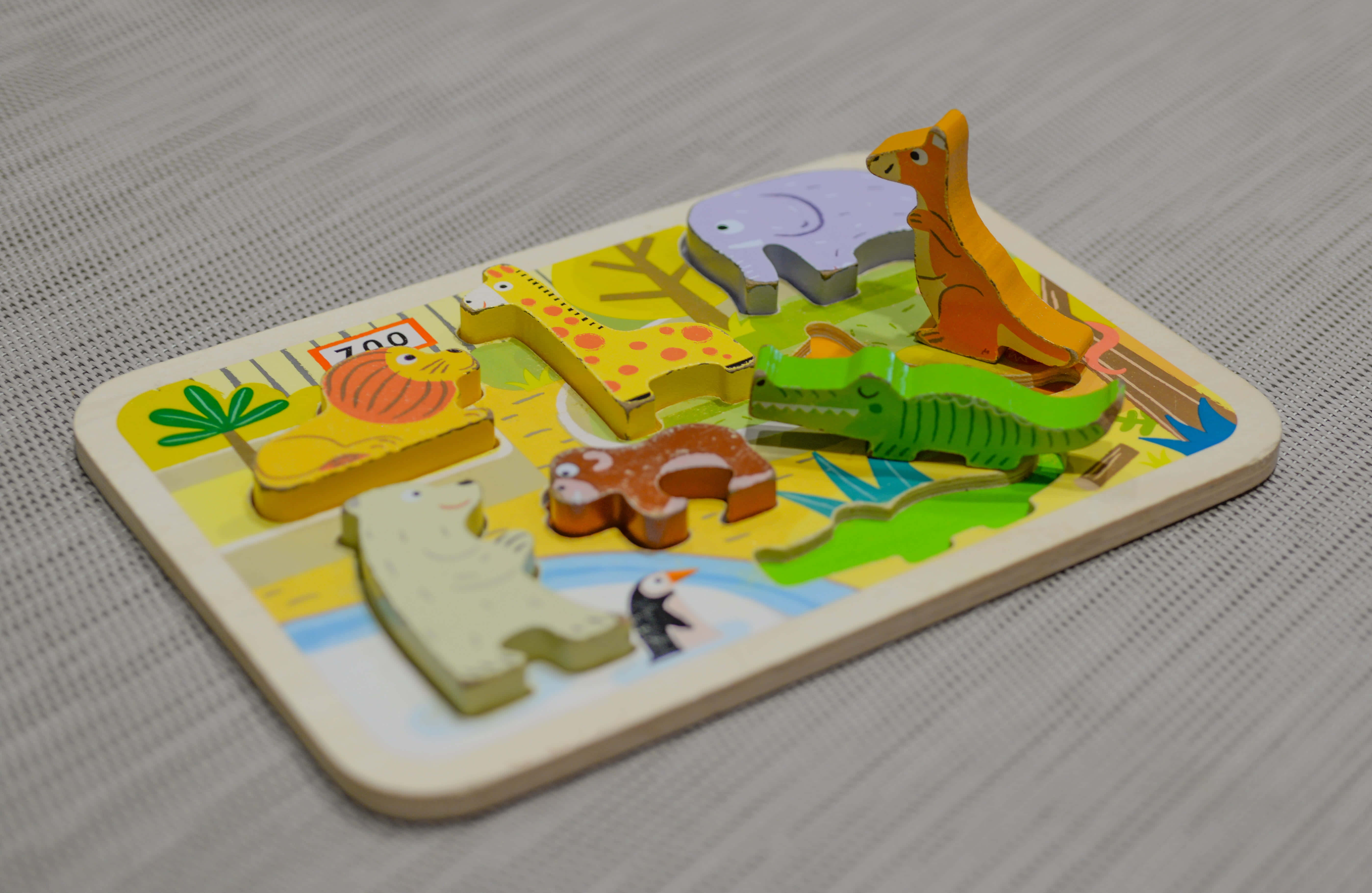 Educational Games 桌布 壁紙 — 一個色彩繽紛的木製動物拼圖，拼塊形狀為長頸鹿、袋鼠、大象和企鵝，放在有紋理的灰色表面上。