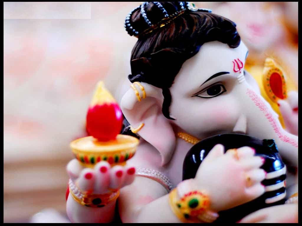 laxmi ganesh saraswati 桌布 壁紙 — 一個色彩繽紛的象神神像特寫，手持點燃的迪亞燈，飾有精緻珠寶，表情寧靜。