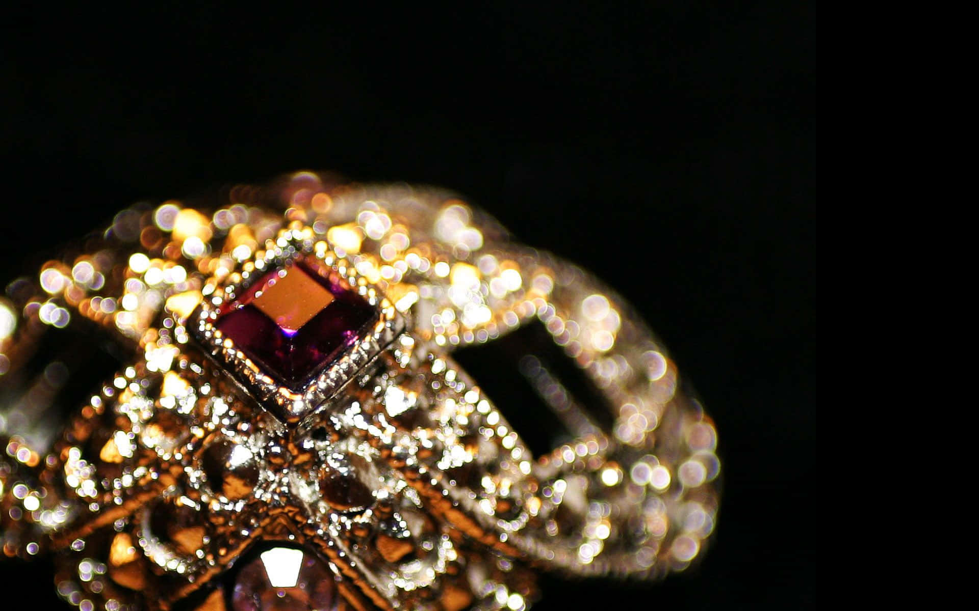 Jewelry Design 桌布 壁紙 — 一個華麗的金色皇冠特寫，飾有閃閃發光的鑽石和中央的紫色寶石，背景為黑色。