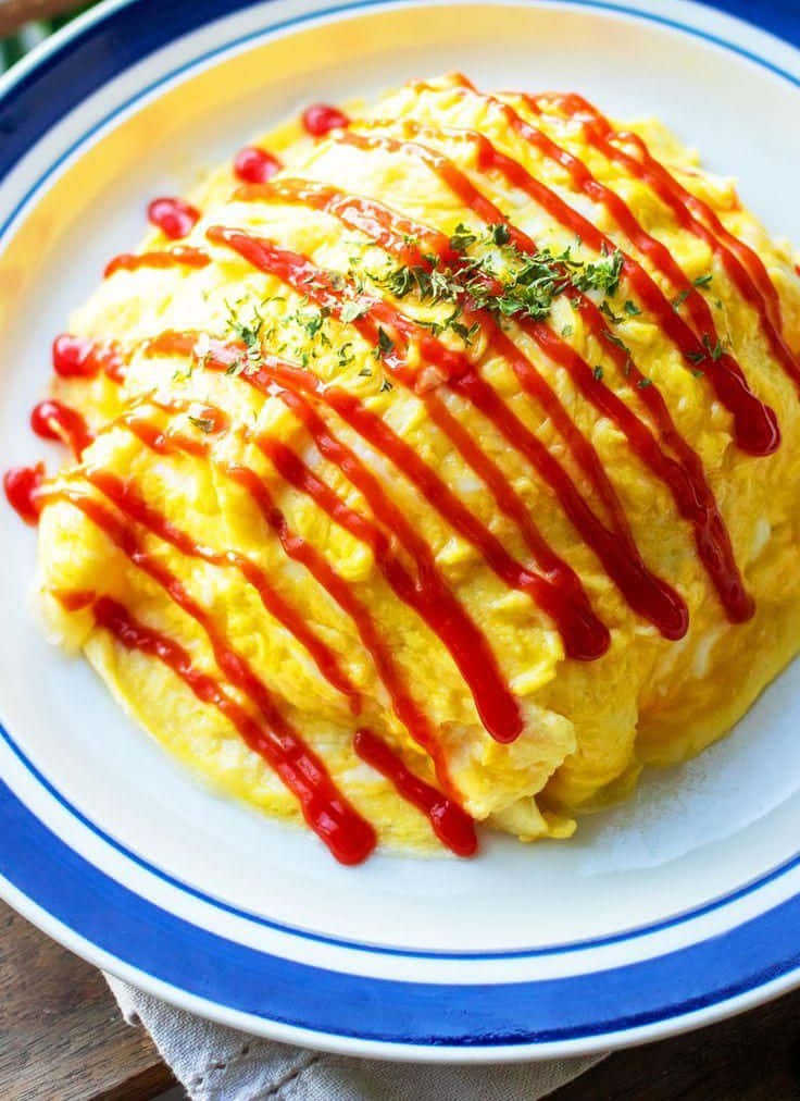 Delicious Food 桌布 壁紙 — 一個蓬鬆金黃色的奄列，淋上鮮紅色的醬汁，並以新鮮綠色香草點綴，放在藍邊碟上。
