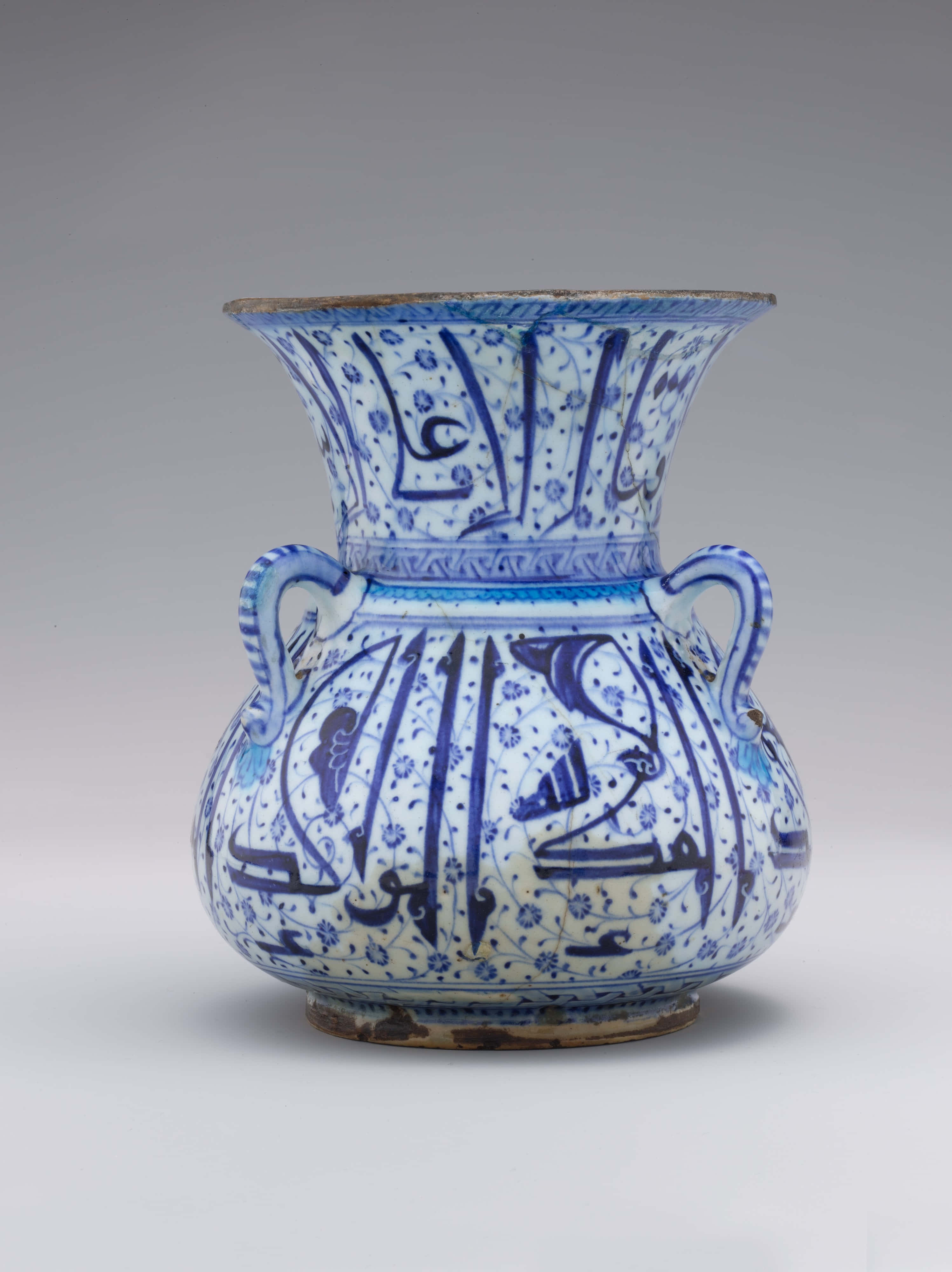 Ceramic 桌布 壁紙 — 一個藍白陶瓷花瓶，飾有複雜的阿拉伯書法和花卉圖案，帶有兩個手柄和一個喇叭形邊緣。