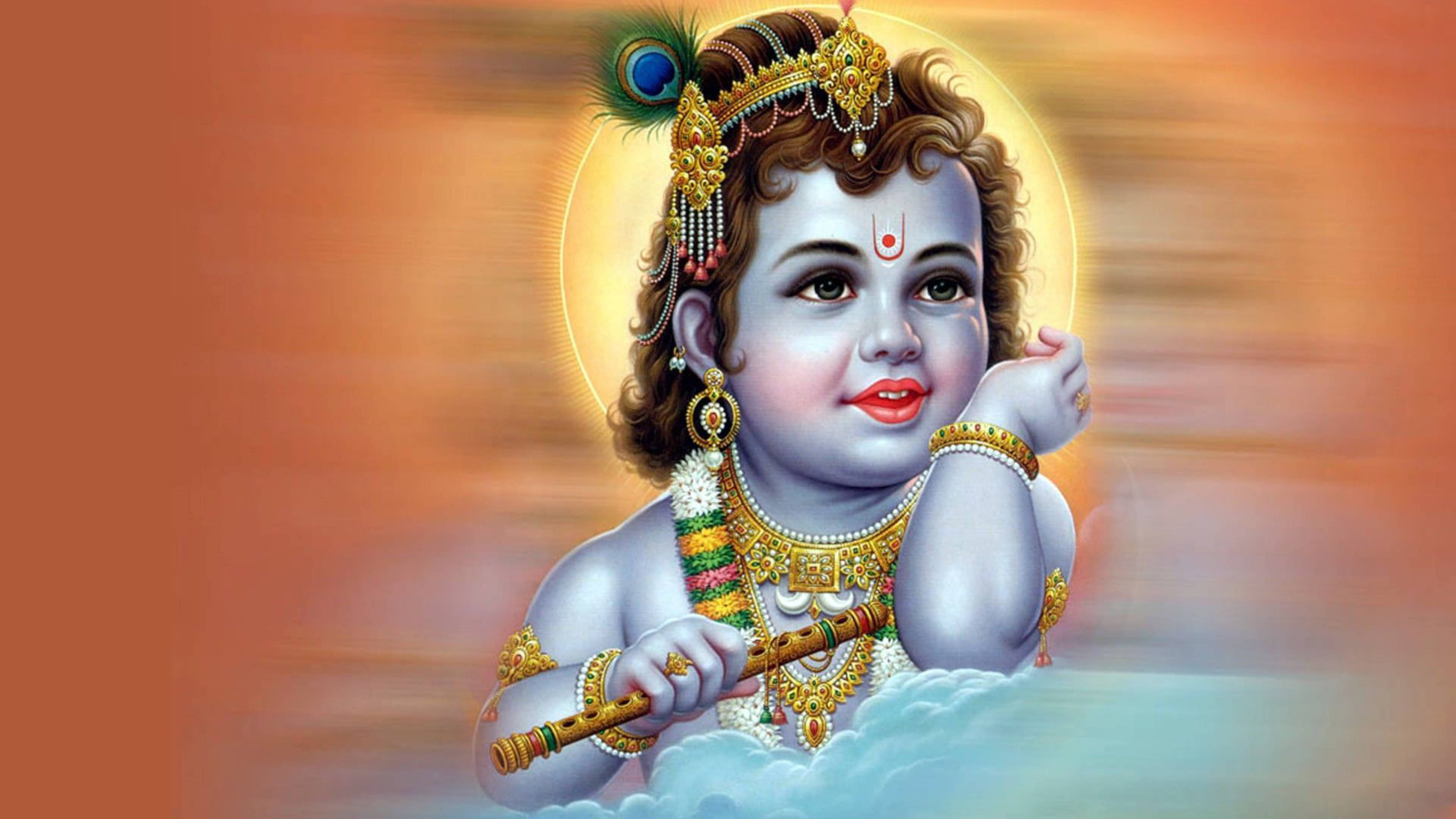 krishna ji 桌布 壁紙 — 一個藍皮膚、戴金冠的神聖孩子坐在雲端上吹奏長笛，背景是耀眼的橙色光環。