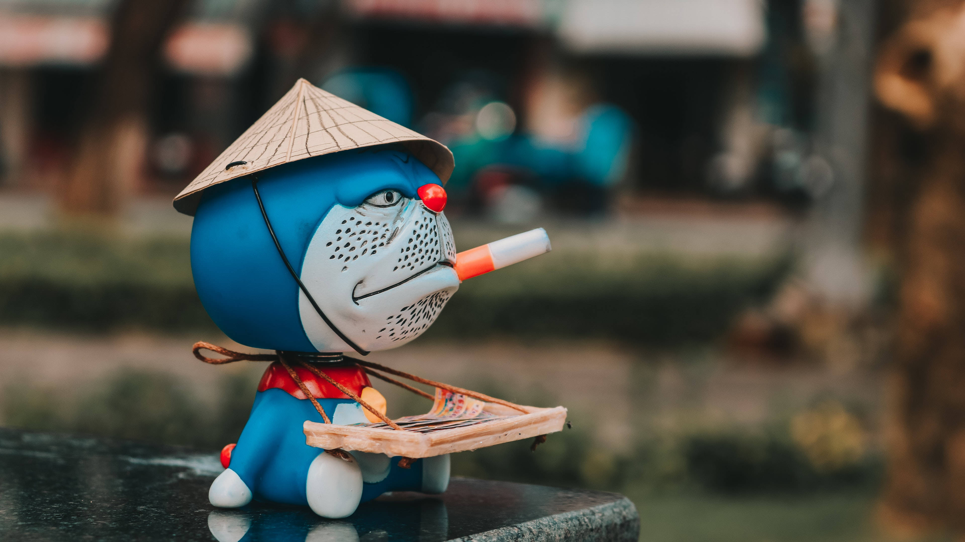 Doraemon 桌布 壁紙 — 一個藍色卡通角色，戴著圓錐形帽子，抽著煙，手持一個小木托盤。
